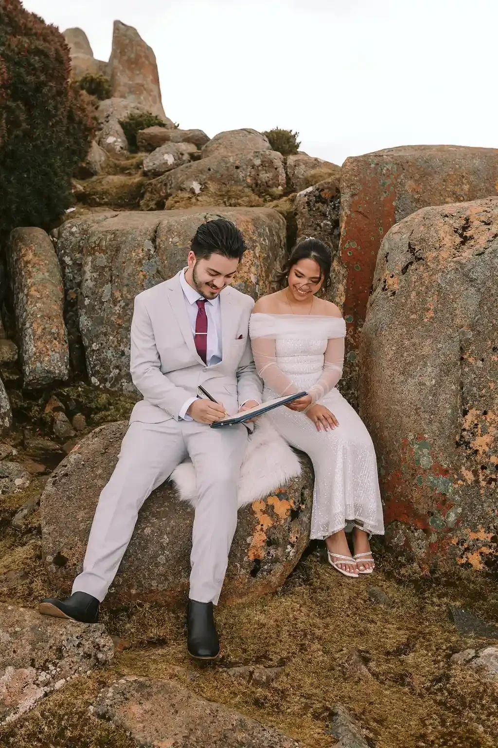 Couple eloping at Cataract Gorge Launceston signing their marriage paperwork on the rocks with I Do Drive Thru — elopement celebrant from $400