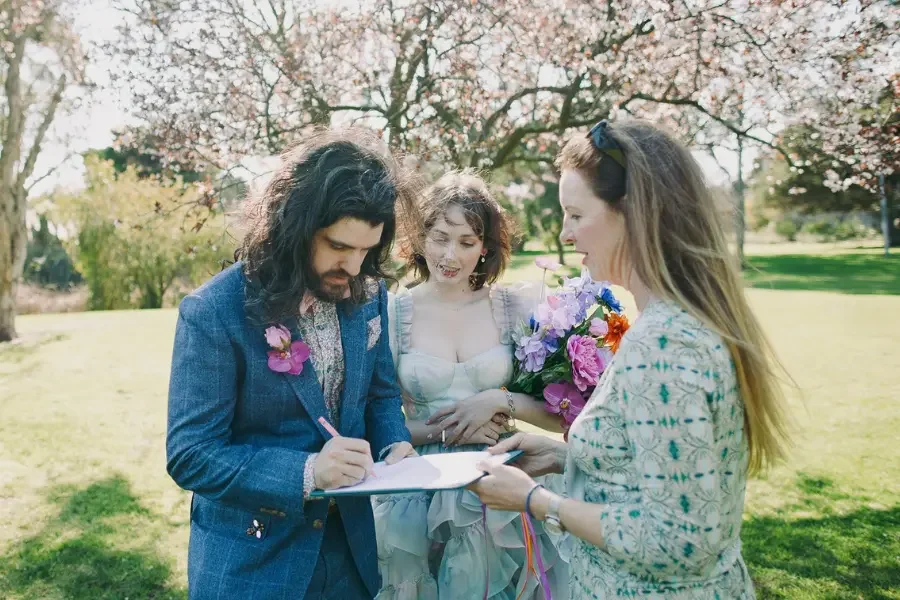 I Do Drive Thru celebrant signing marriage paperwork with a newly married couple at Fitzroy Gardens Melbourne