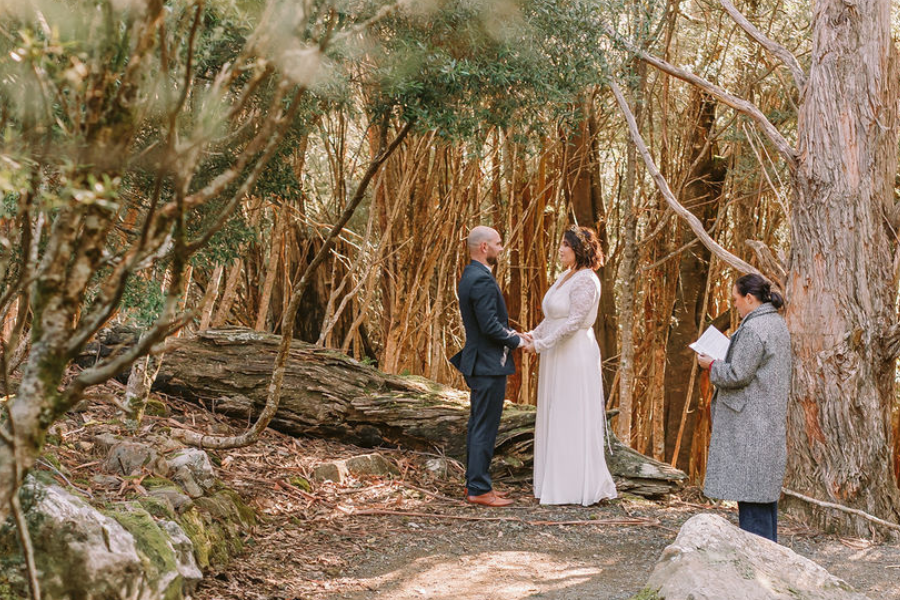 Budget wedding couple smiling outdoors with celebrant and photographer