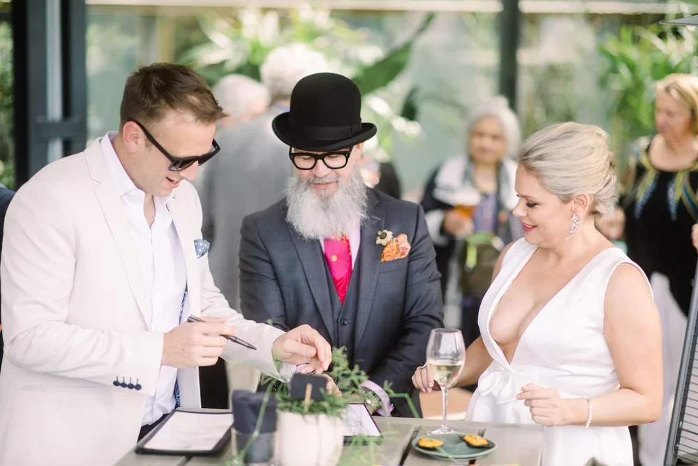 I Do Drive Thru celebrant signing marriage paperwork at a bar wedding with guests celebrating — wedding ceremony from $800