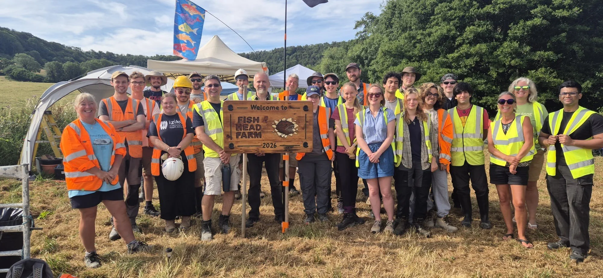 a group of people in high vis jackets stood around a wooden sign saying Fish Head Farm 2026