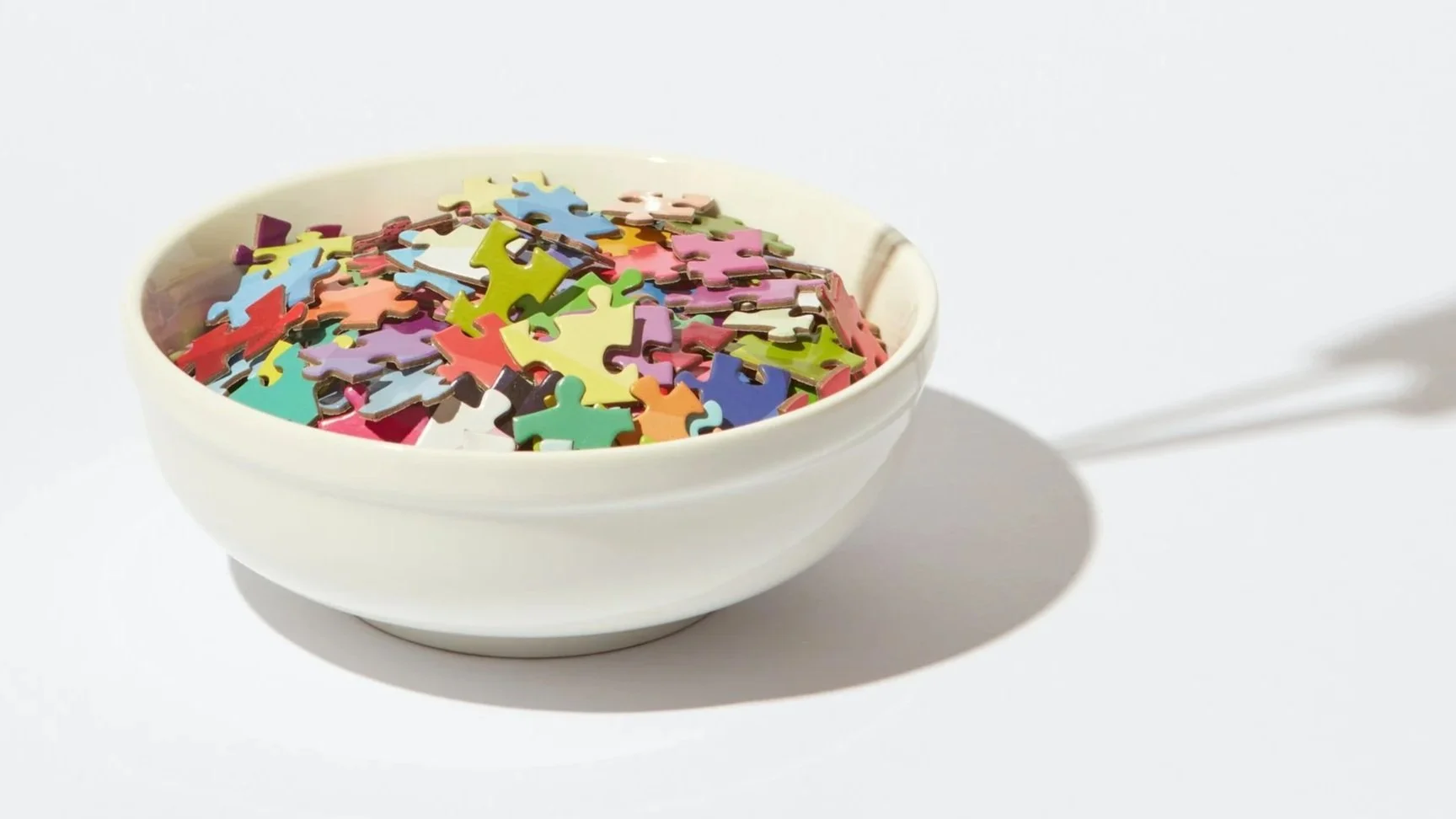 Colourful puzzle pieces in a bowl representing ADHD, impulsive eating and brain regulation