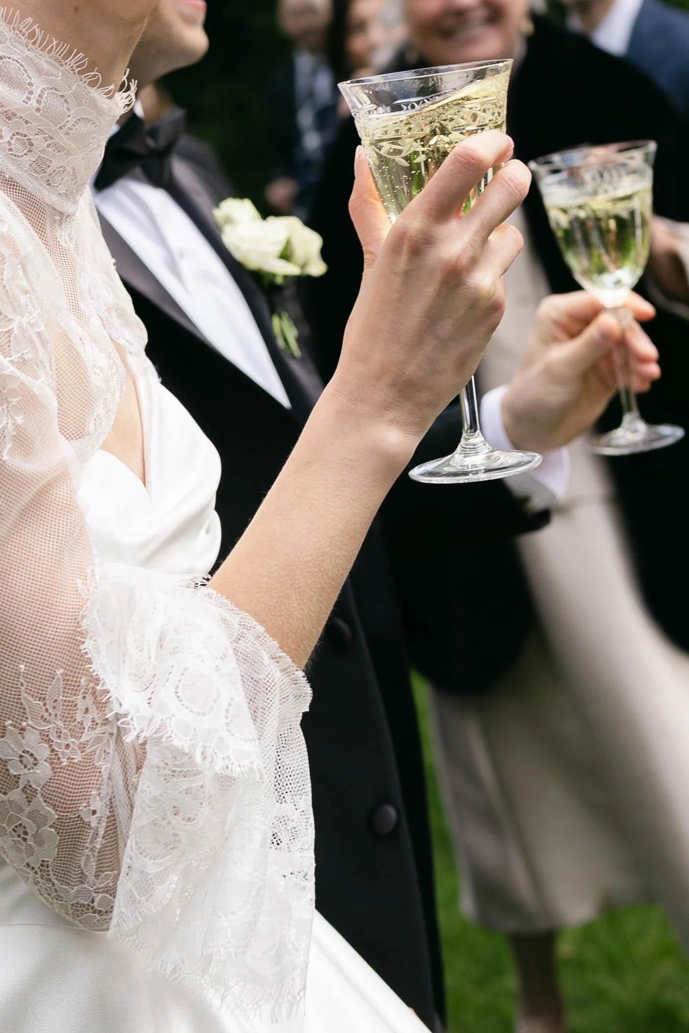 Close-up of a bride and groom holding champagne glasses at a wedding celebration.
