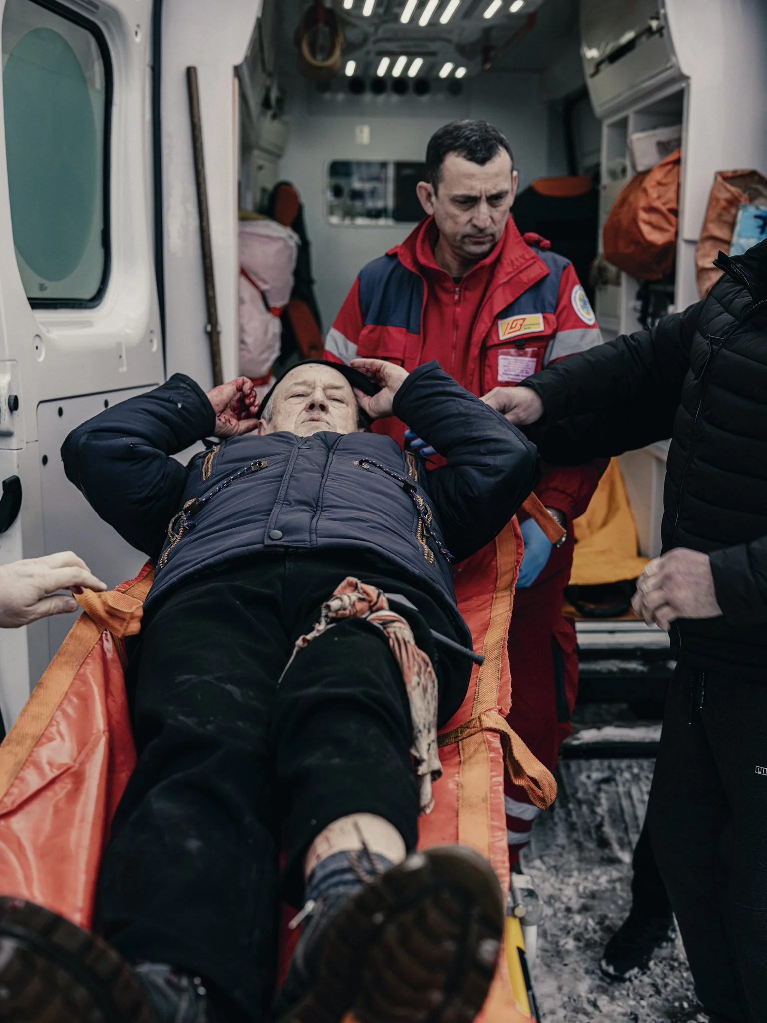 Emergency medical personnel attending to a patient lying on a stretcher inside an ambulance.