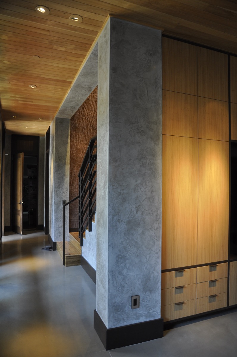 Grey plaster columns and warm wood are part of a rich material palette.