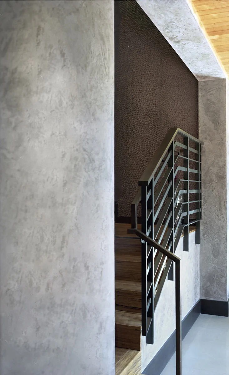 The black rail of the staircase sets off the grey wall.