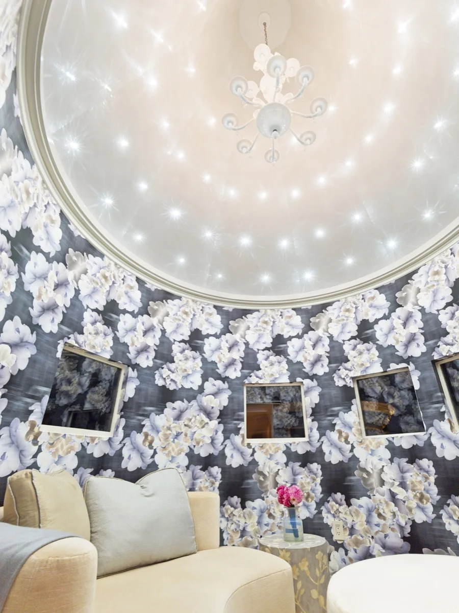 Floral wallpaper beneath a domed plaster ceiling set with lights.