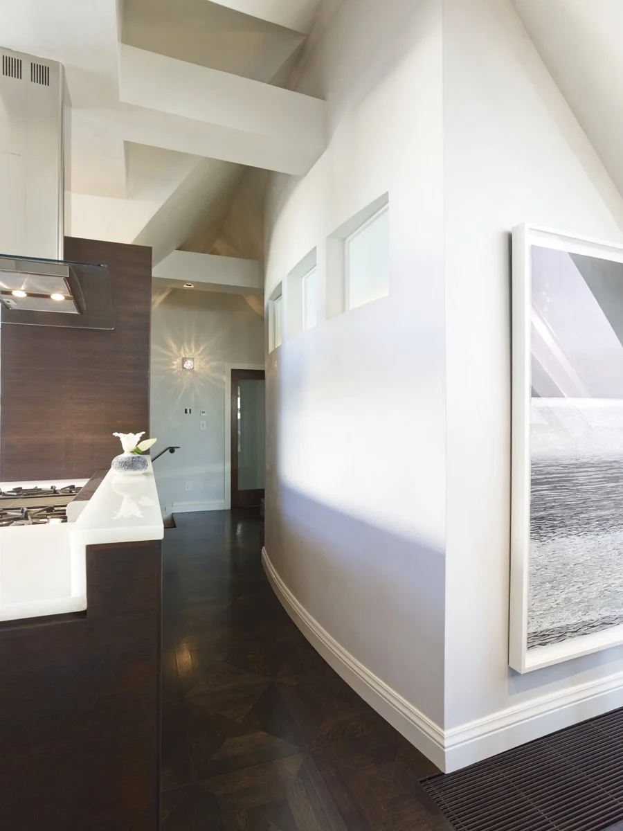 An integral-color curved plaster wall travels past the kitchen.