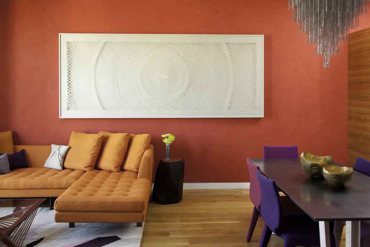 The room features a bold palette of red, orange, purple and warm tones from the interior designer.