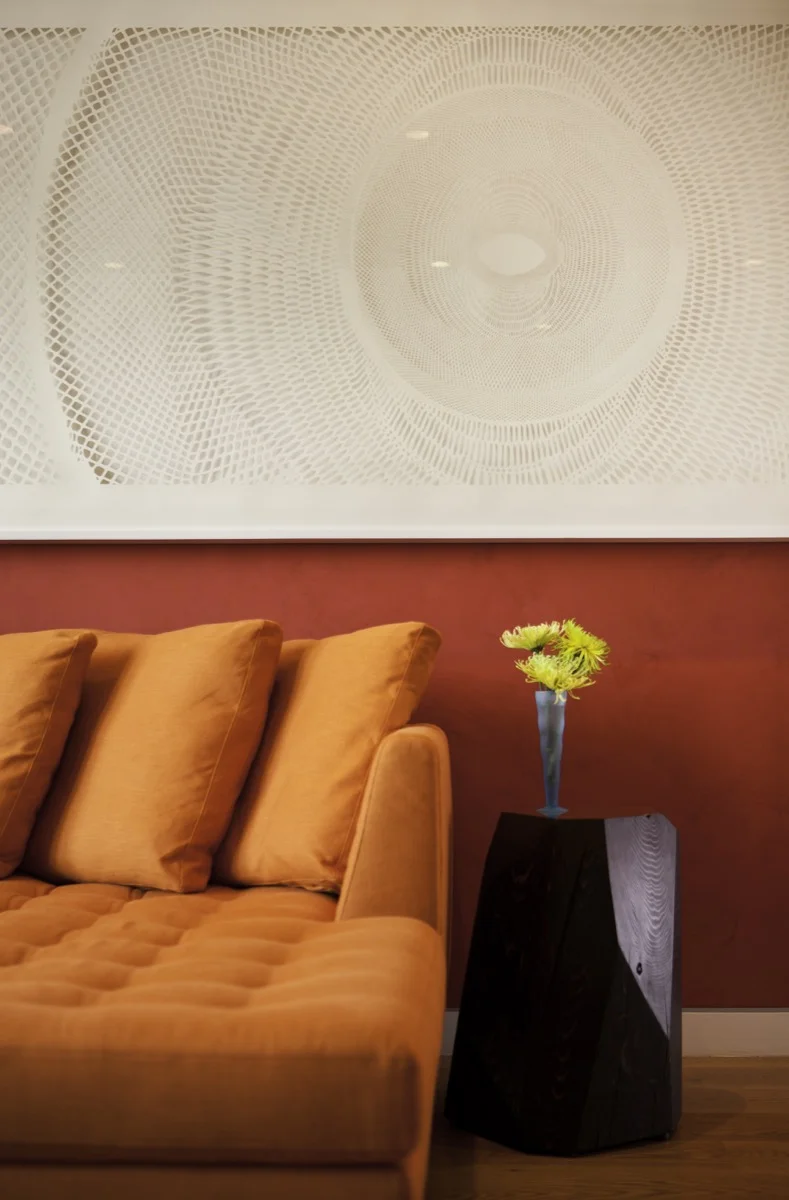 The red wall sets off the a piece of art that is a single tone of white.