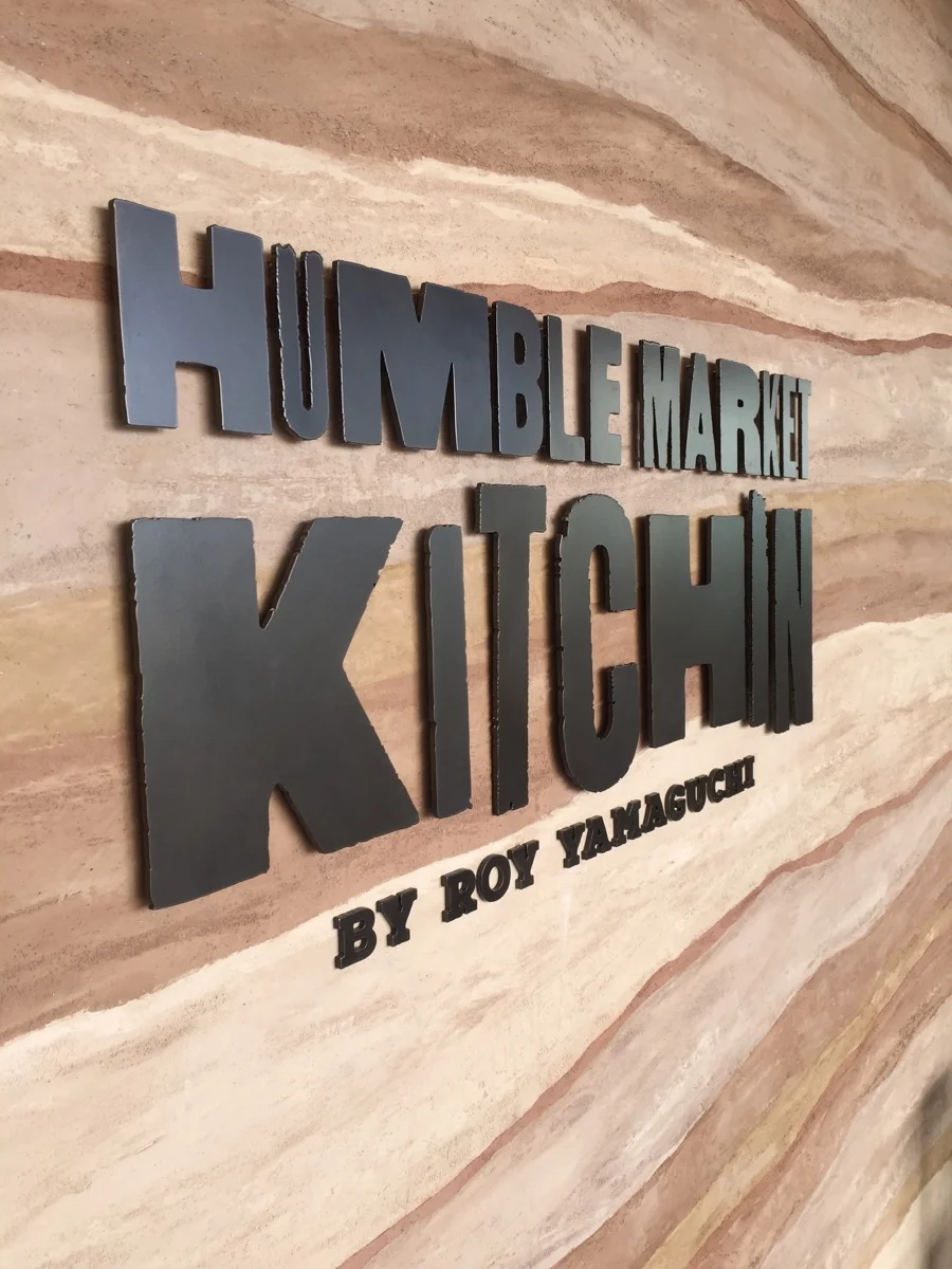 The restaurant’s sign is set off by the geo-strata plaster wall.
