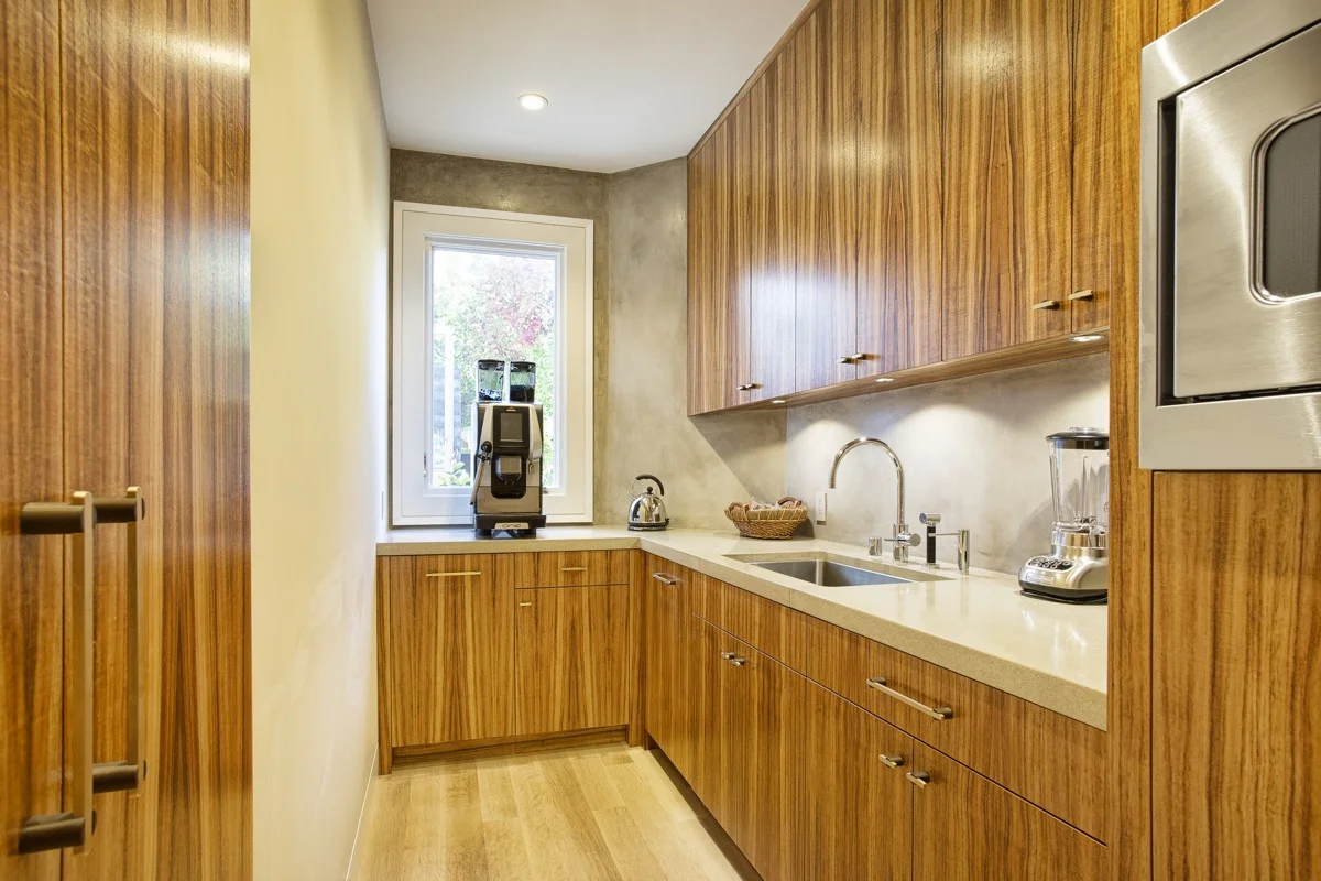 The pantry has the same integral color plaster finish and wood cabinets as the kitchen in this San Francisco home.