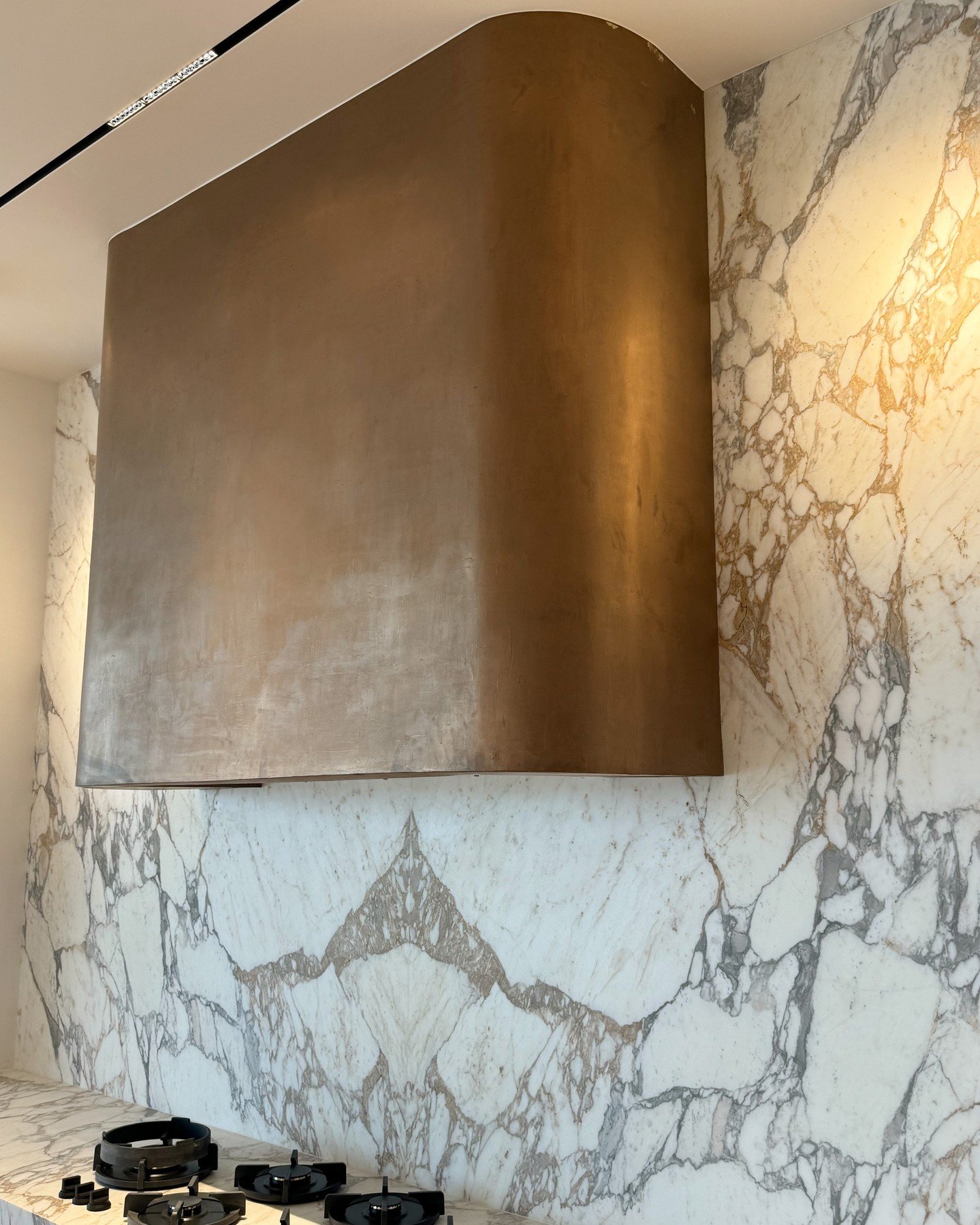 A sculptural metal plaster hood becomes a defining moment in the space, balancing material richness with understated drama. #inspo #originalby @californiawalldesign