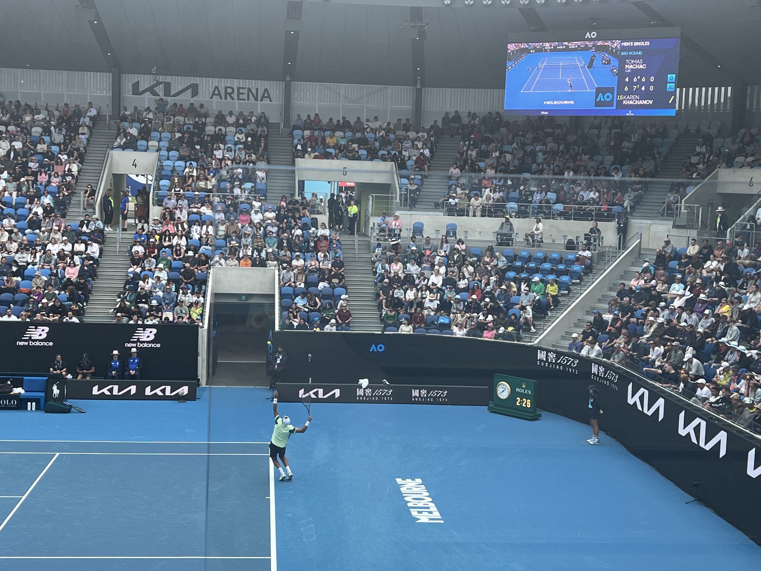    Image 2: A photo of a male tennis player serving during a match at Kia Arena.   