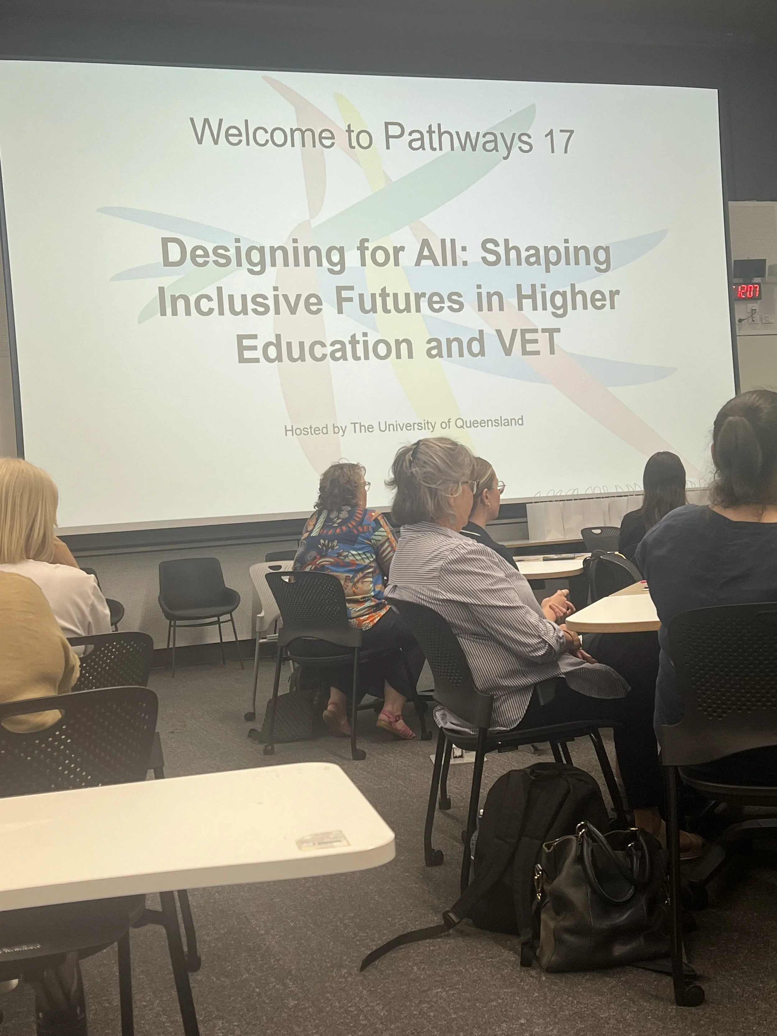 A Photo of a projector screen with the words Welcome to Pathways 17  Designing for All: Shaping Inclusive Futures in Higher Education and VET.