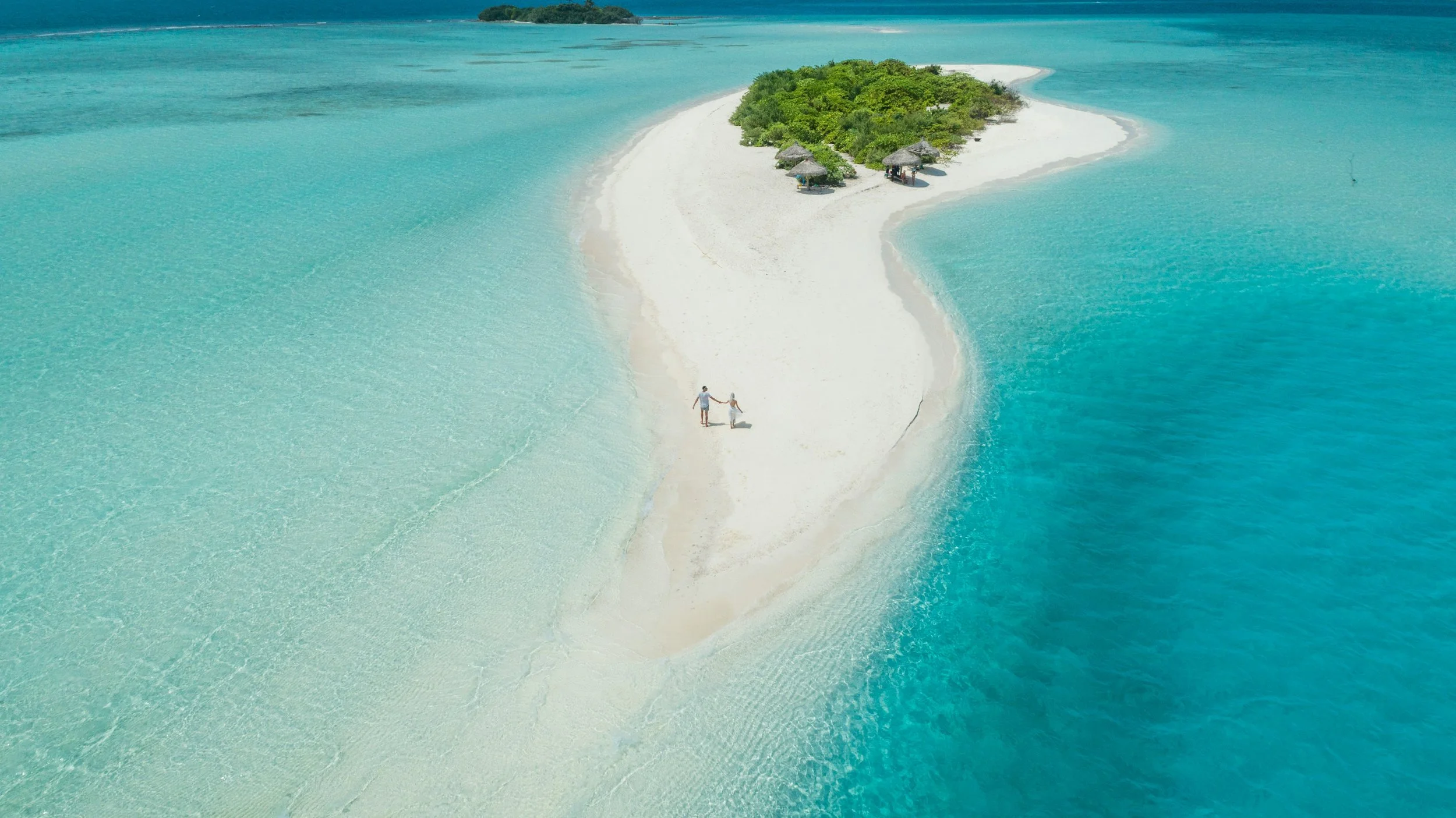 Couple walking on sand bar in the Maldives 