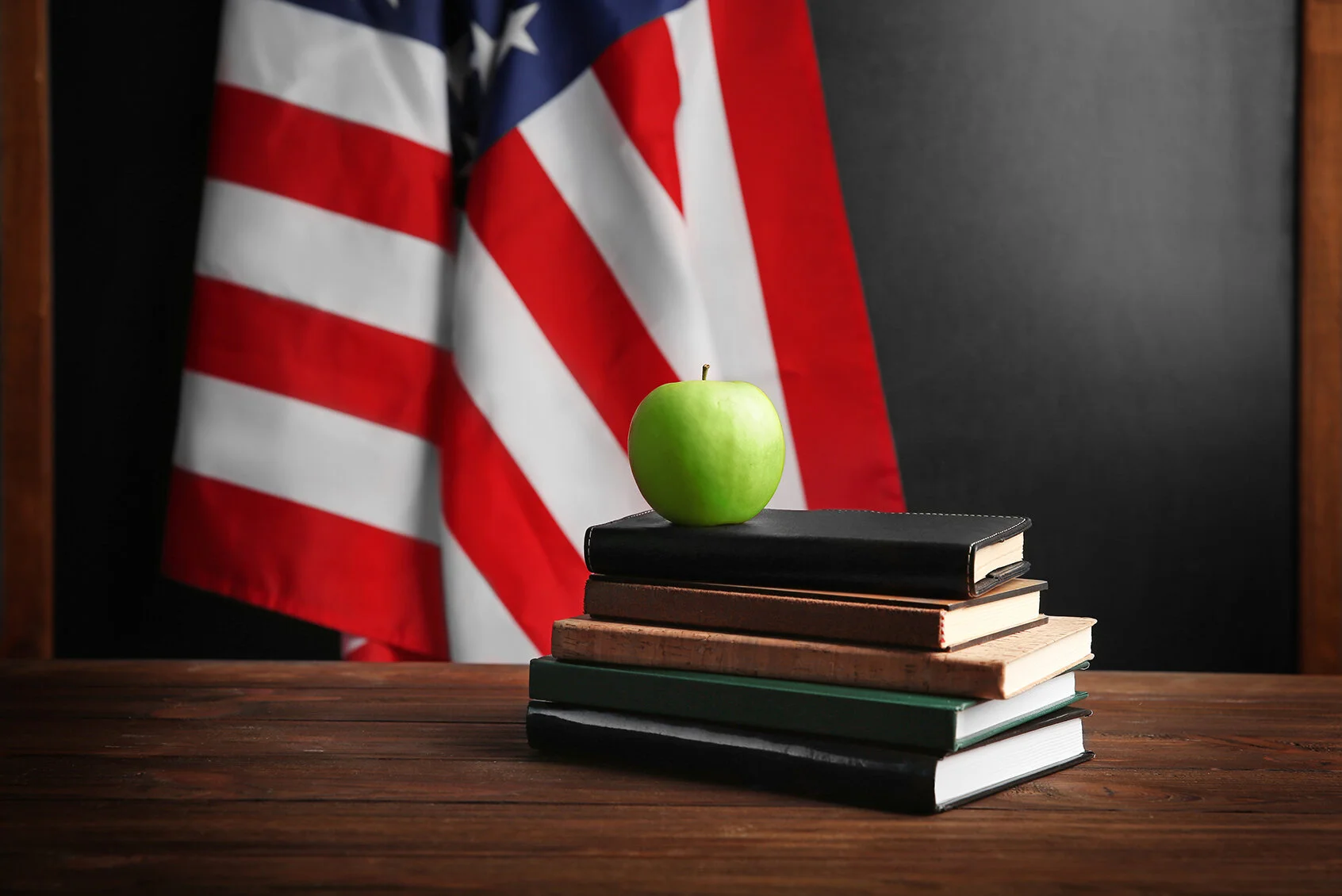 Apple on books with USA flag in front of balckboard.jpg