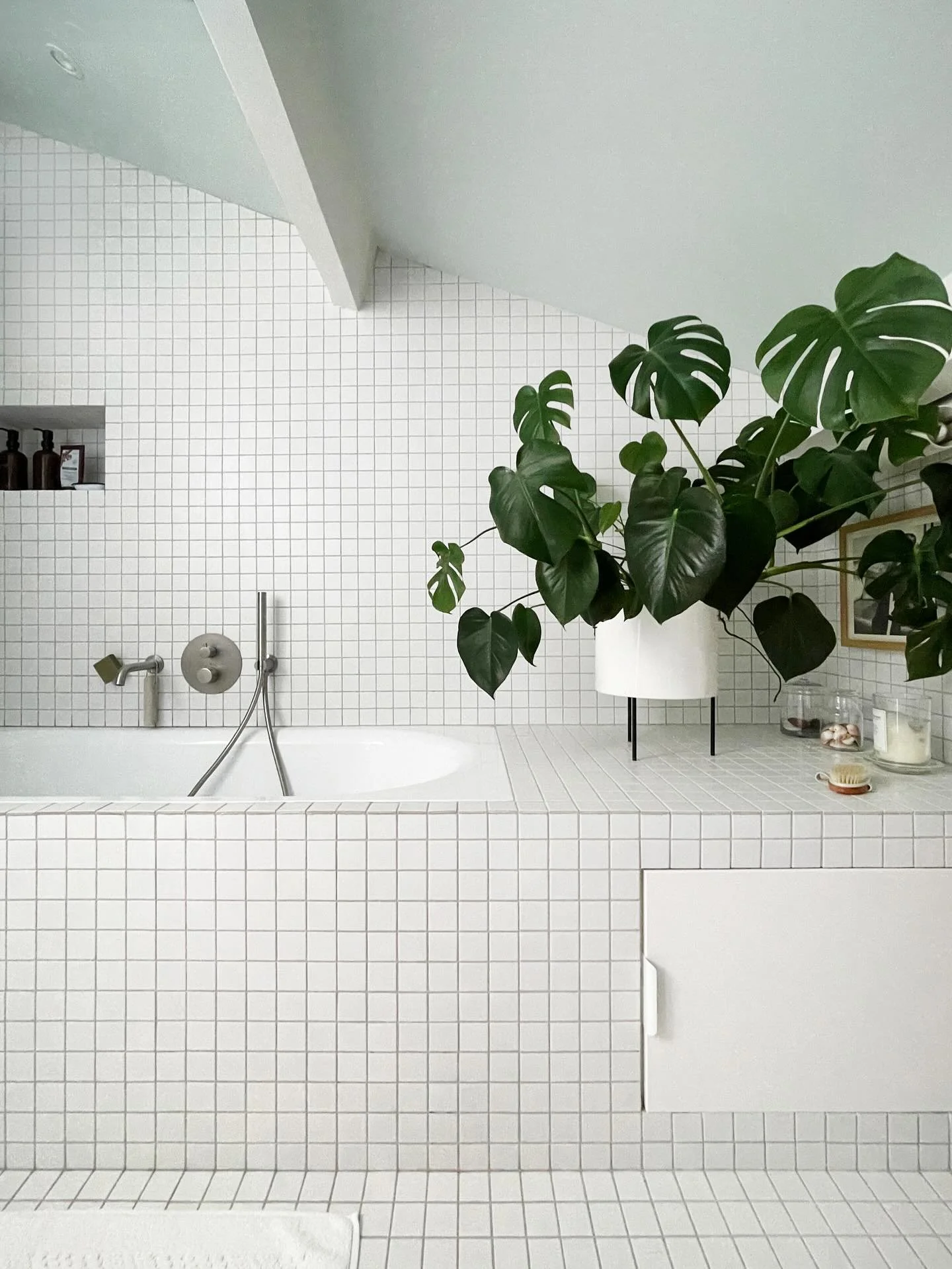 Puret&eacute; du blanc et rigueur du calepinage &eacute;quilibr&eacute;es par la douceur d&rsquo;un plafond l&eacute;g&egrave;rement teint&eacute; et la g&eacute;n&eacute;rosit&eacute; d&rsquo;une plante tropicale, et voil&agrave; une salle de bain q