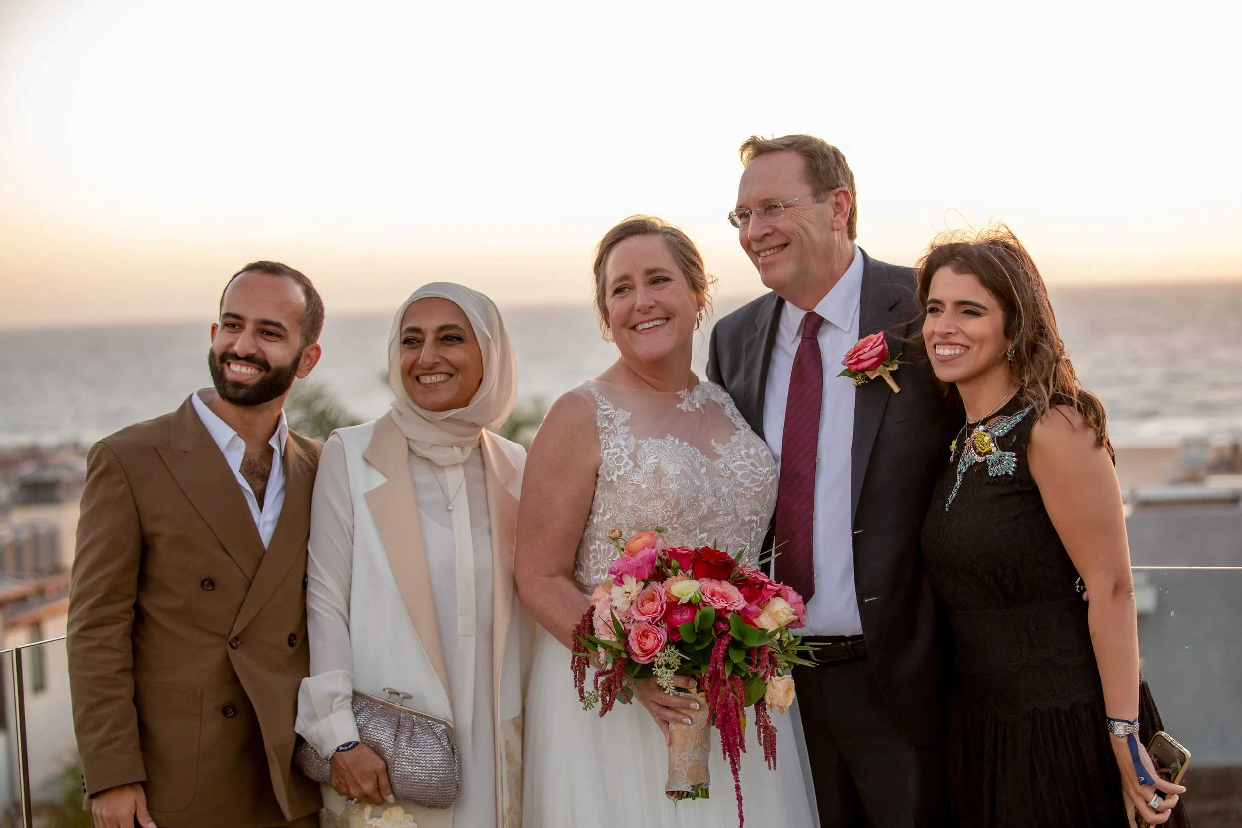  A bridal portrait with guests at the beach at sunset 