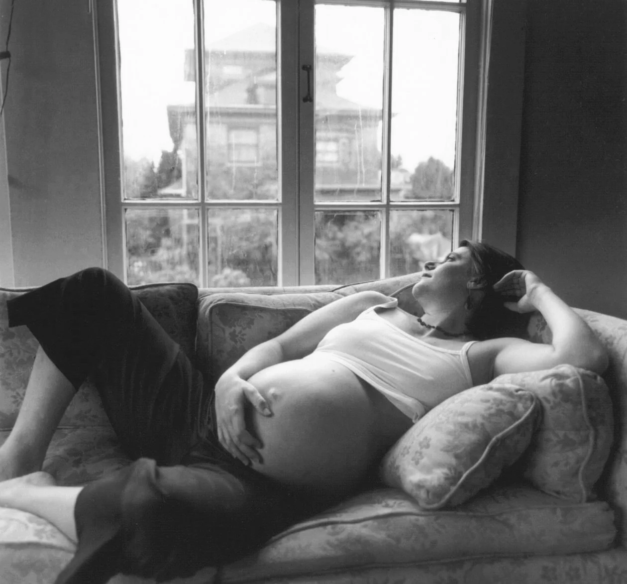 Maternity photographer New York woman on a couch by a window