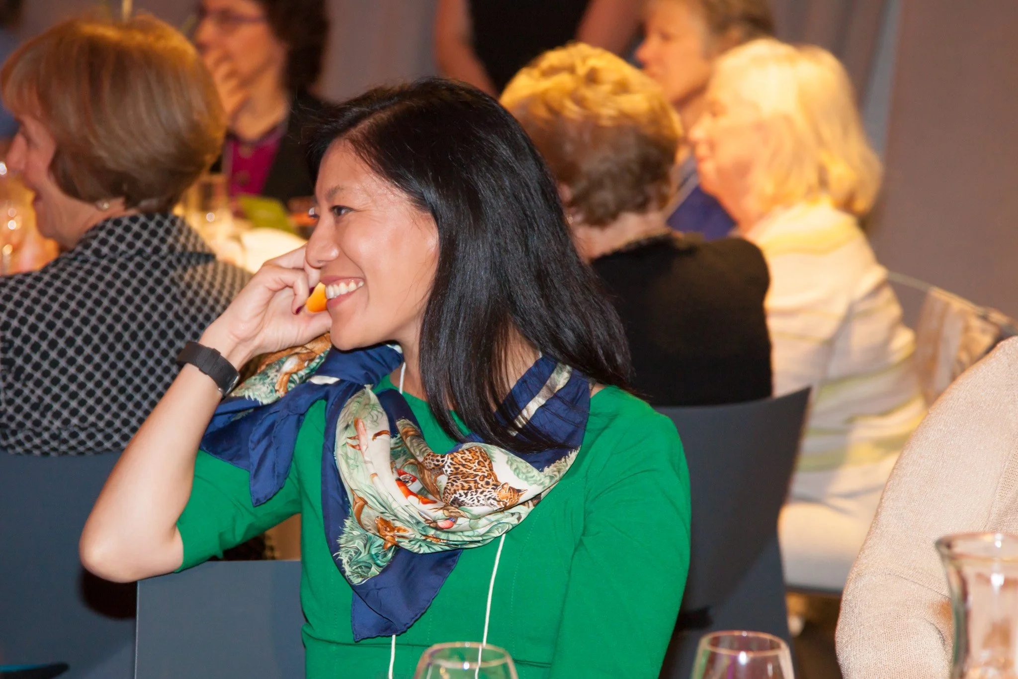  Woman at a banquet table smiles and listens to a speaker, at an NYC Fundraising event and New York City  