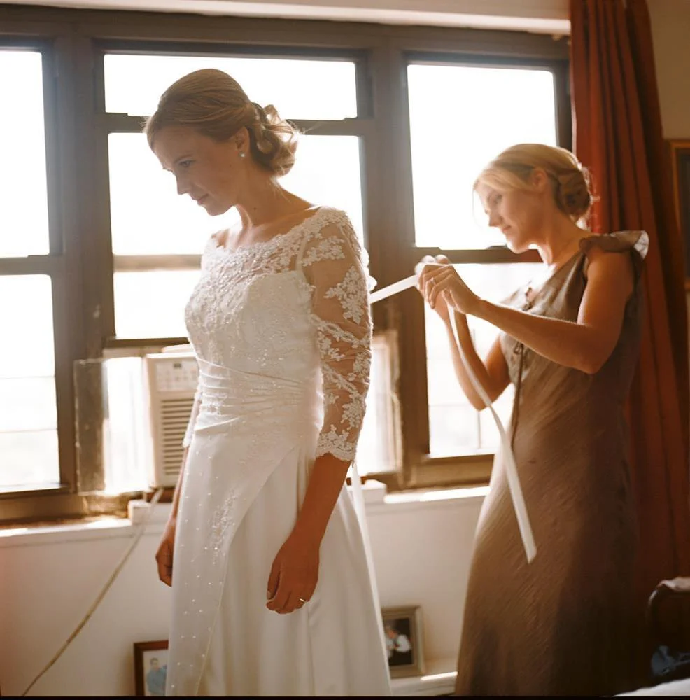 Sister helps bride tie wedding dress