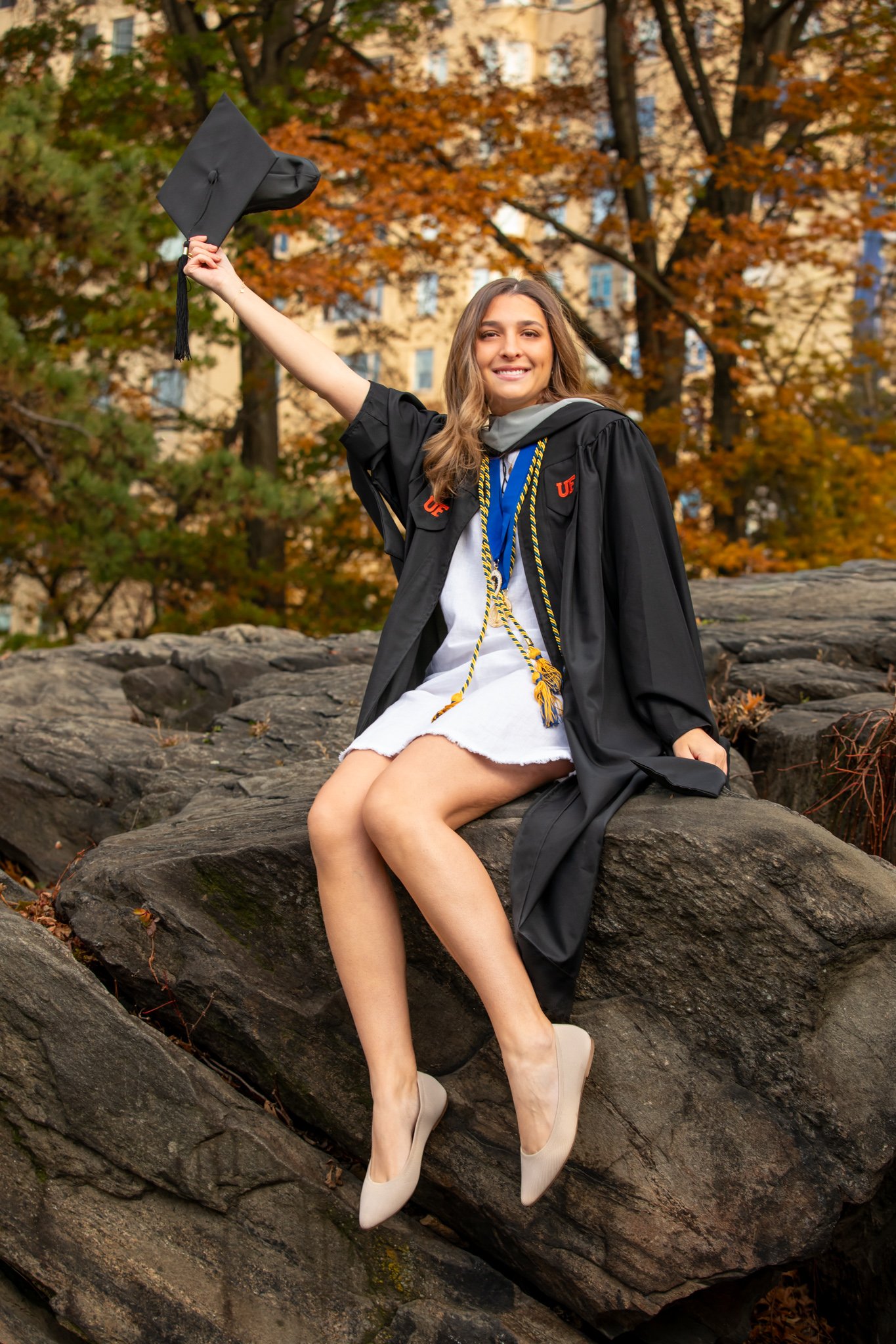 College grad poses atop Manhattan Schist in Central Park NYC