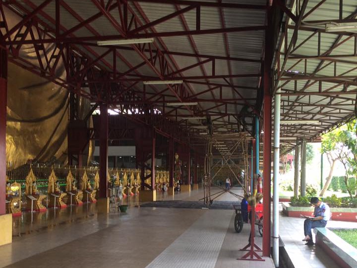 Behind the Buddha (whose golden back is visible on the left), workers on bamboo scaffolding maintain the metal latticework.