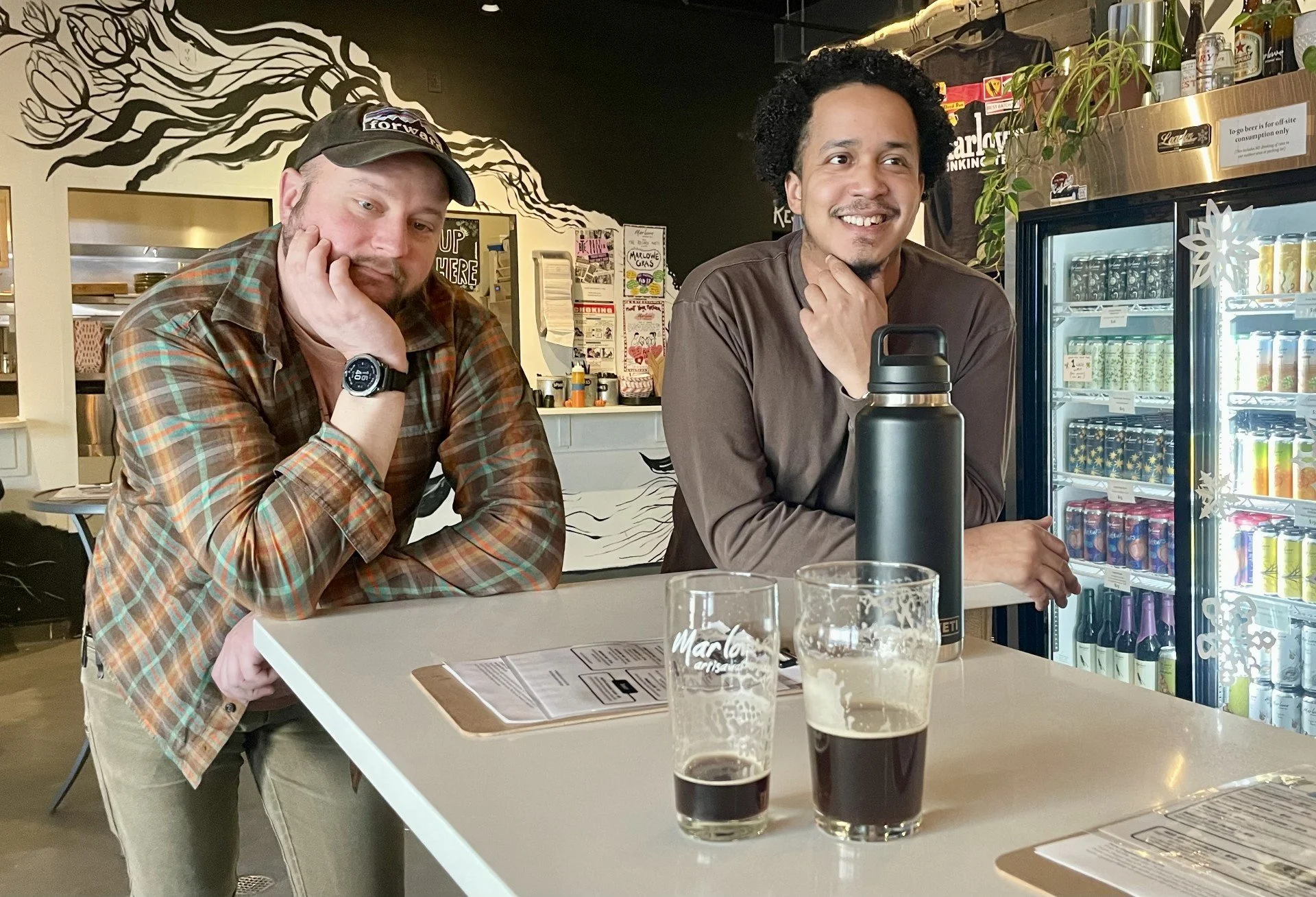 Two dudes behind two beers.