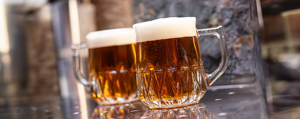 Two Rastal Teku mugs filled with beer.