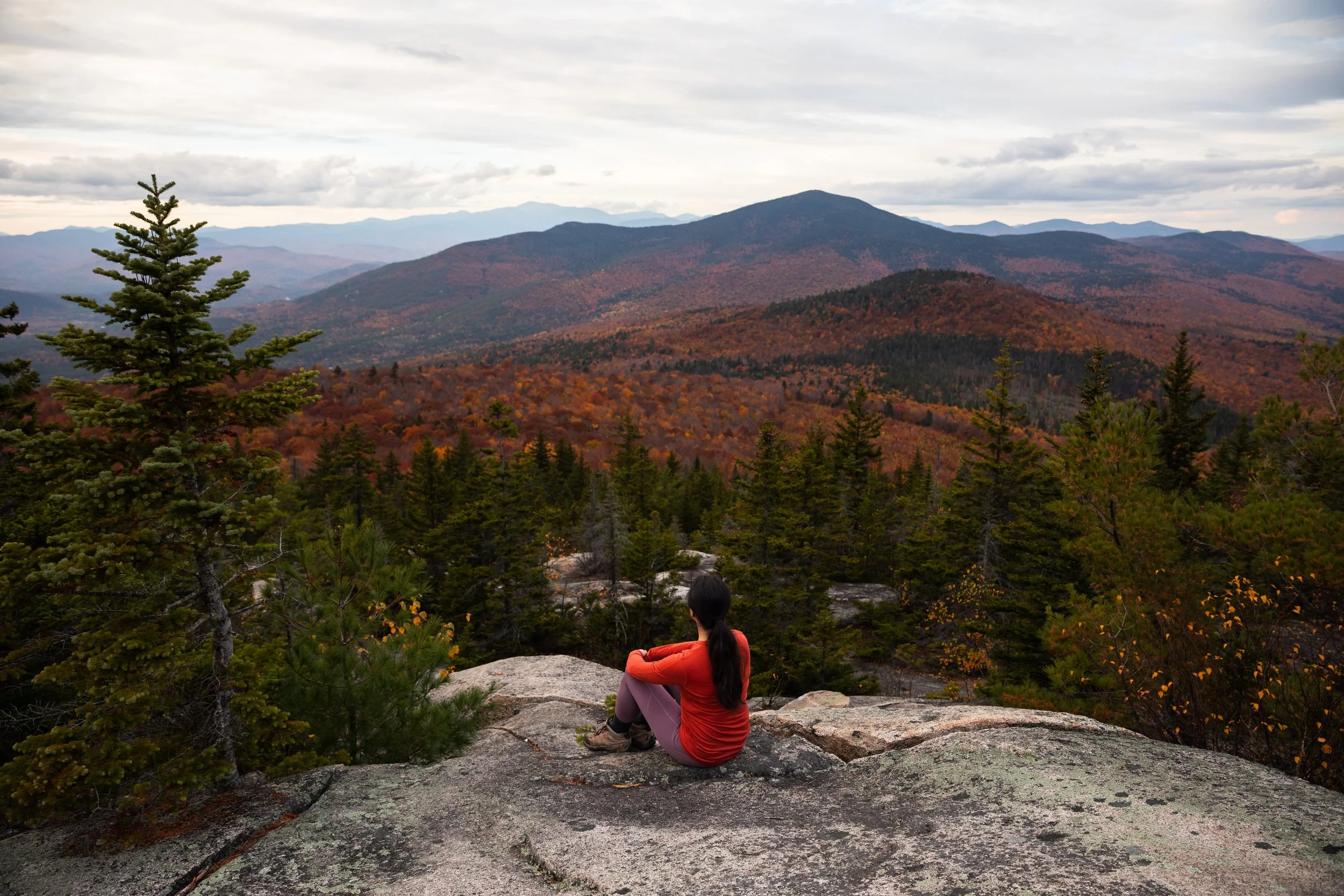 girl sitting on mountain overlooking fall foliage