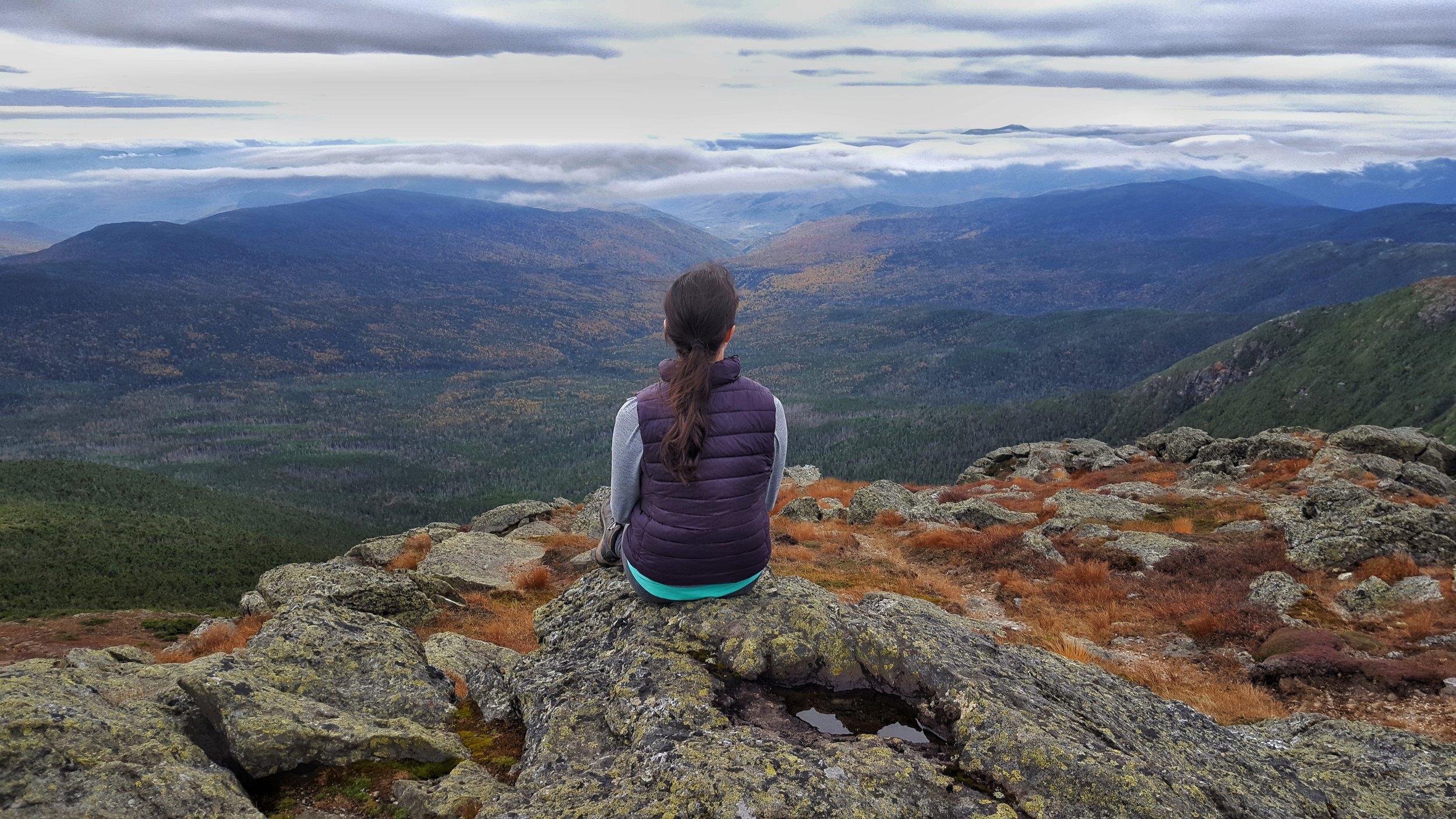 girl sitting on mount washington looking out to mountain views