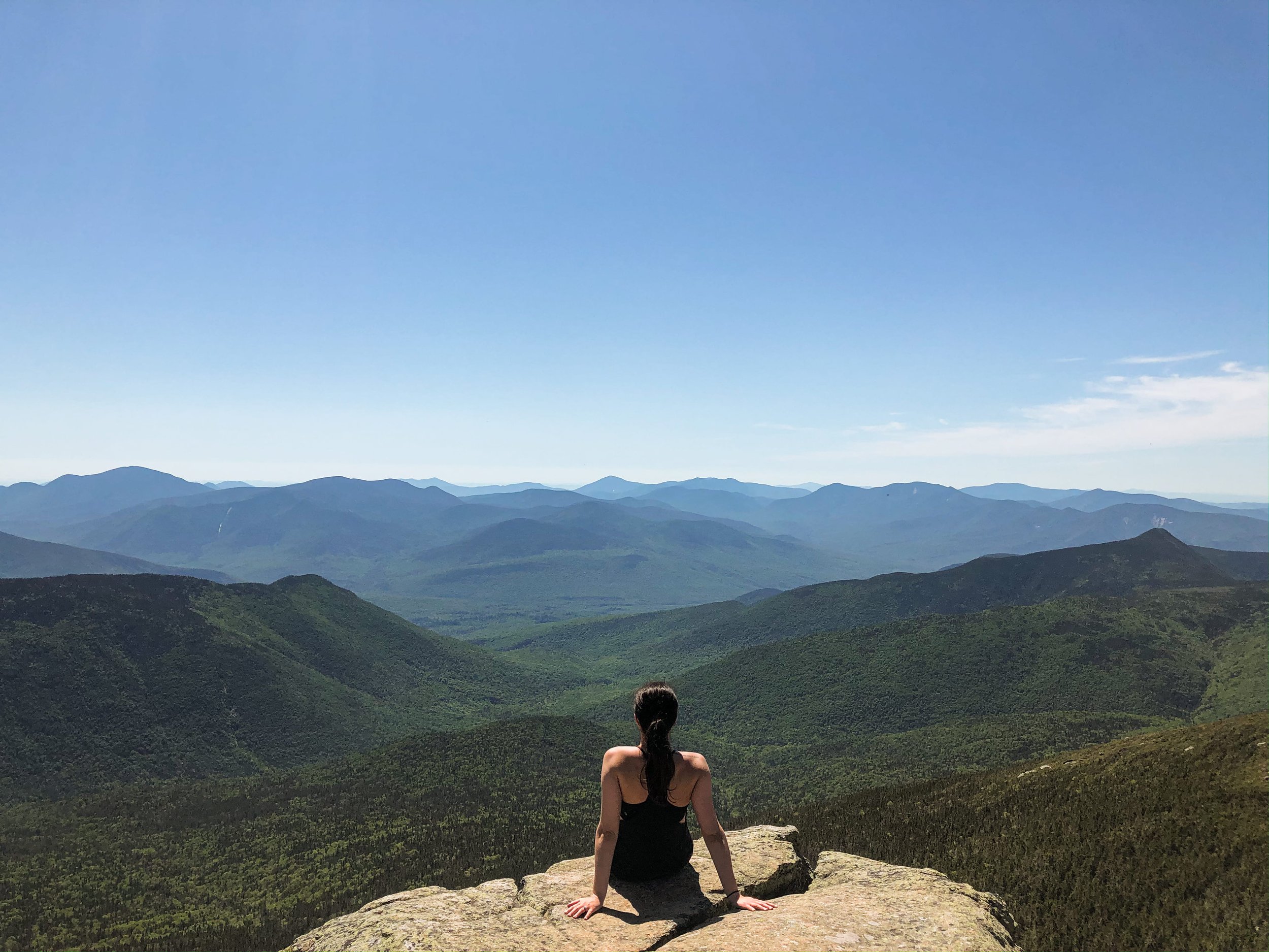 girl sitting on mount lafayette looking out to mountain views
