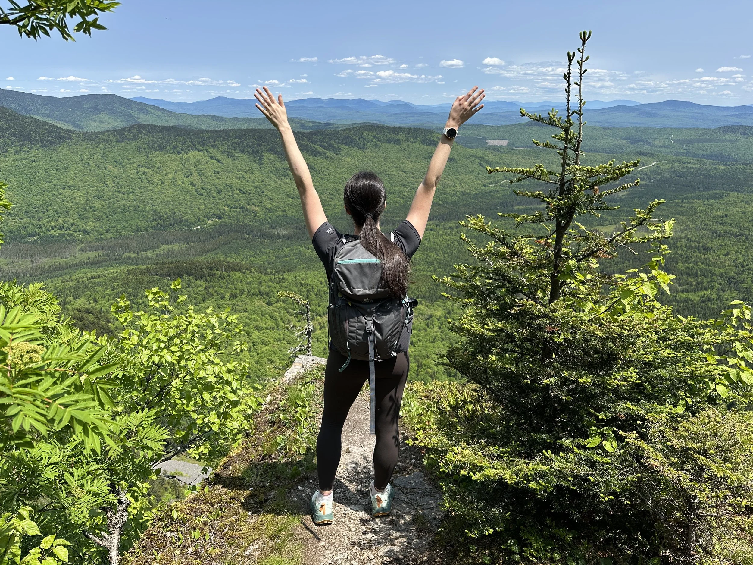 girl standing on mountain with arms up