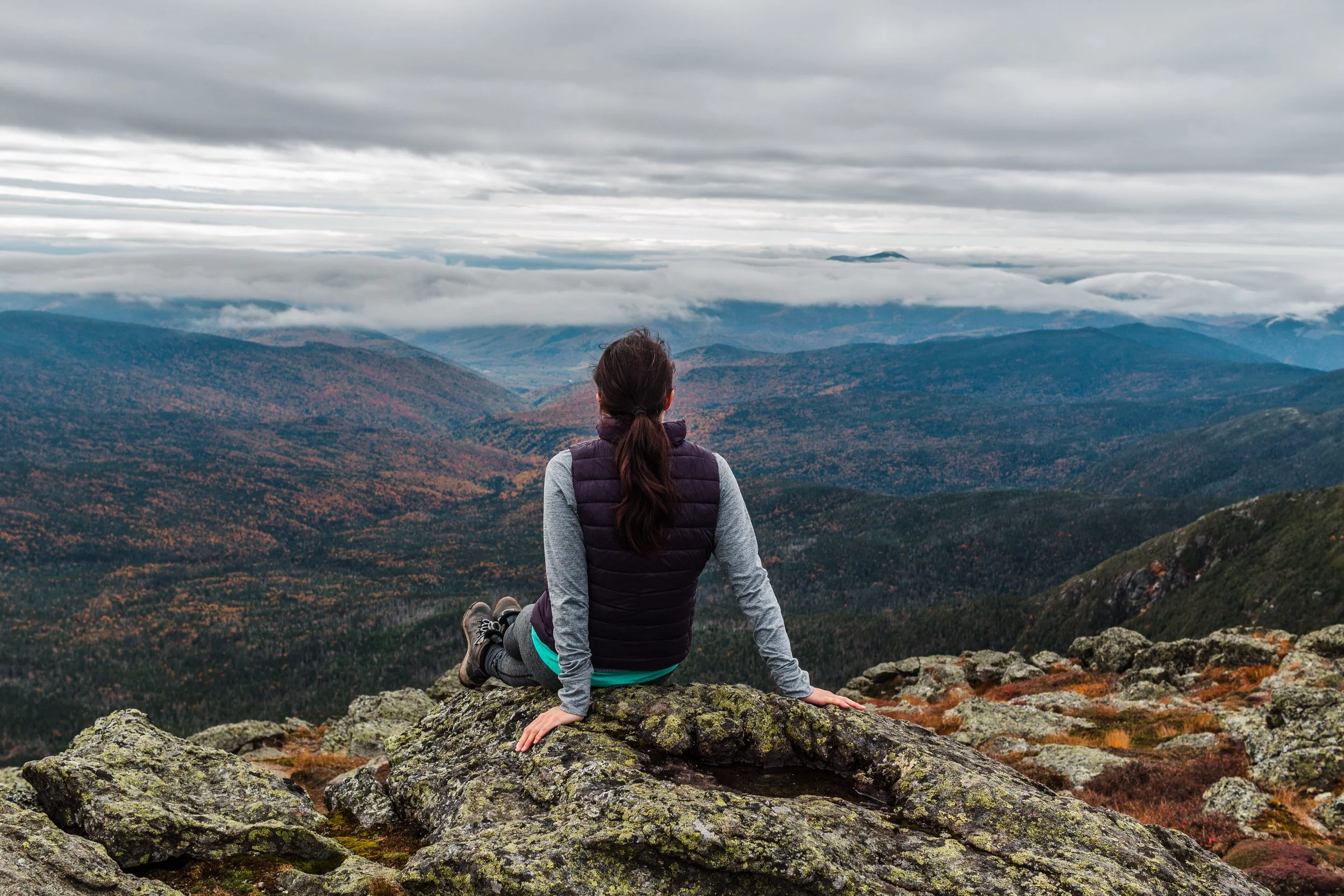 girl sitting on rock overlooking mountains with fall foliage