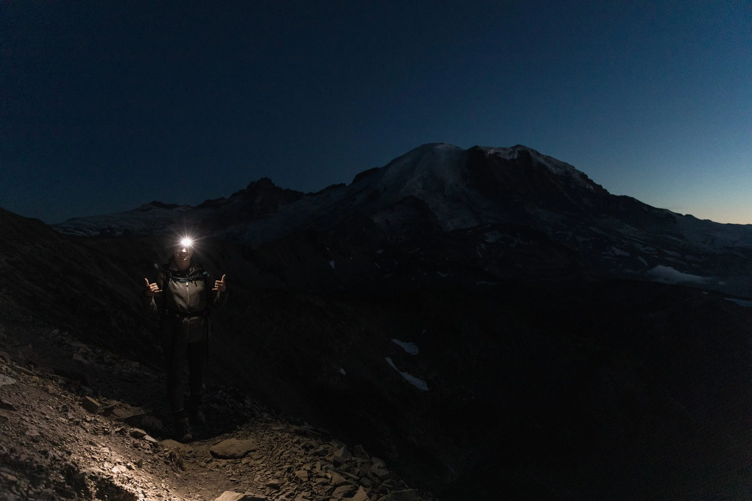 girl hiking in a headlamp with mount rainier in the background