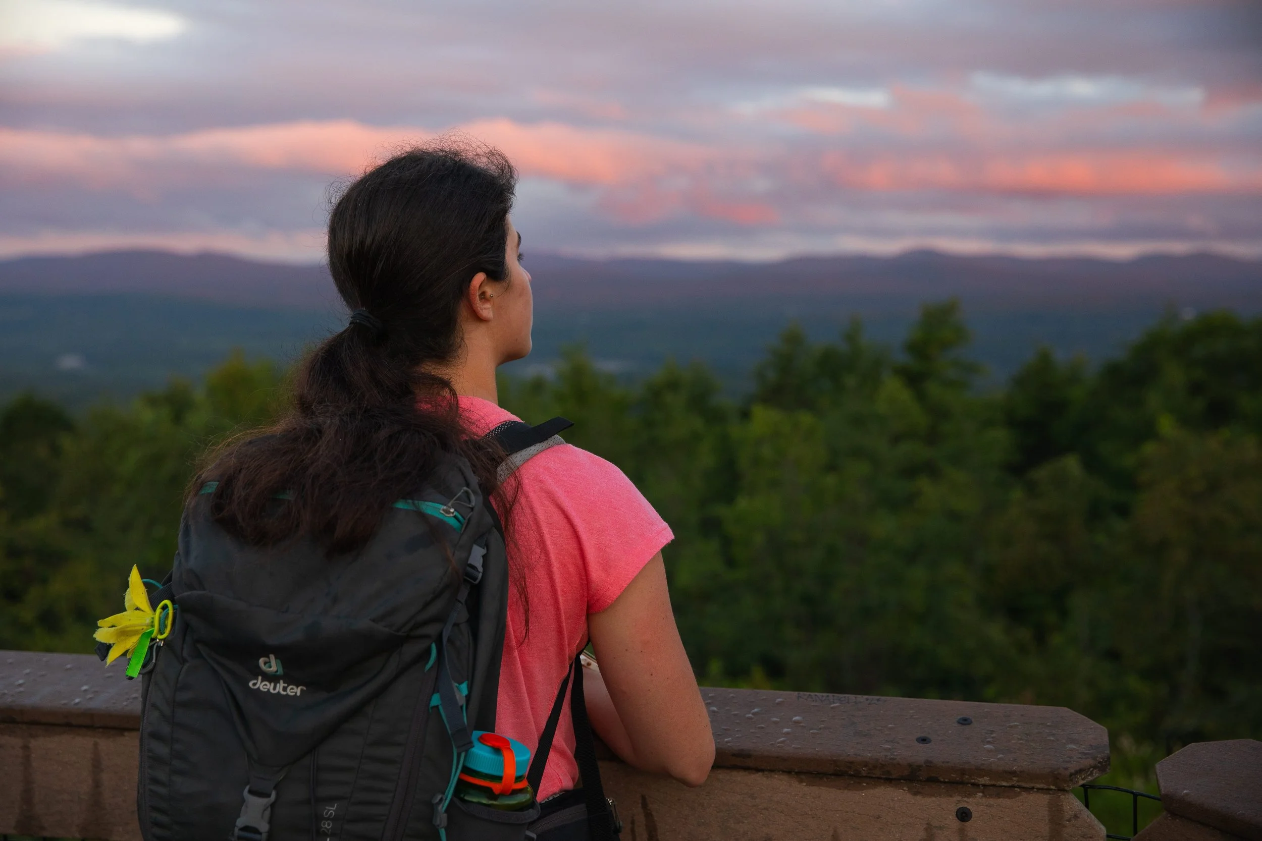 girl standing on mountain overlooking mountains during sunrise