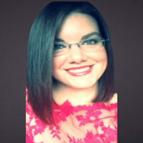 A woman with straight dark hair, glasses, and a bright smile, wearing a pink patterned top.