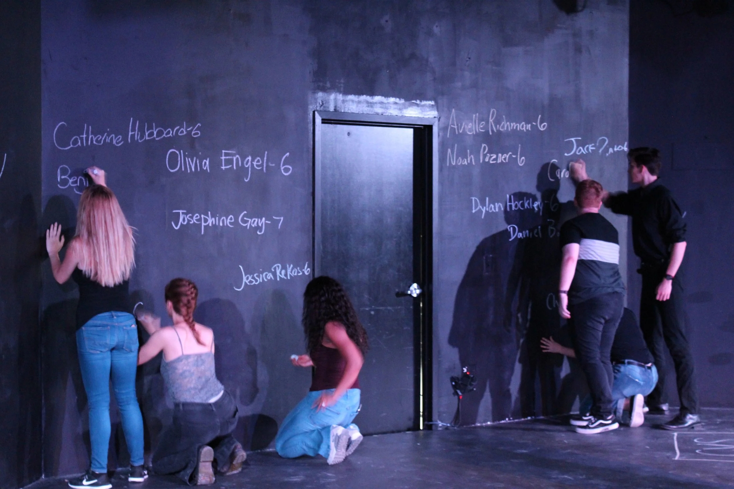 After a difficult scene walking audiences through the events of December 14th, the actors take a moment to write the names of all the victims on the back wall of the theatre. The names remain there for the rest of the play.