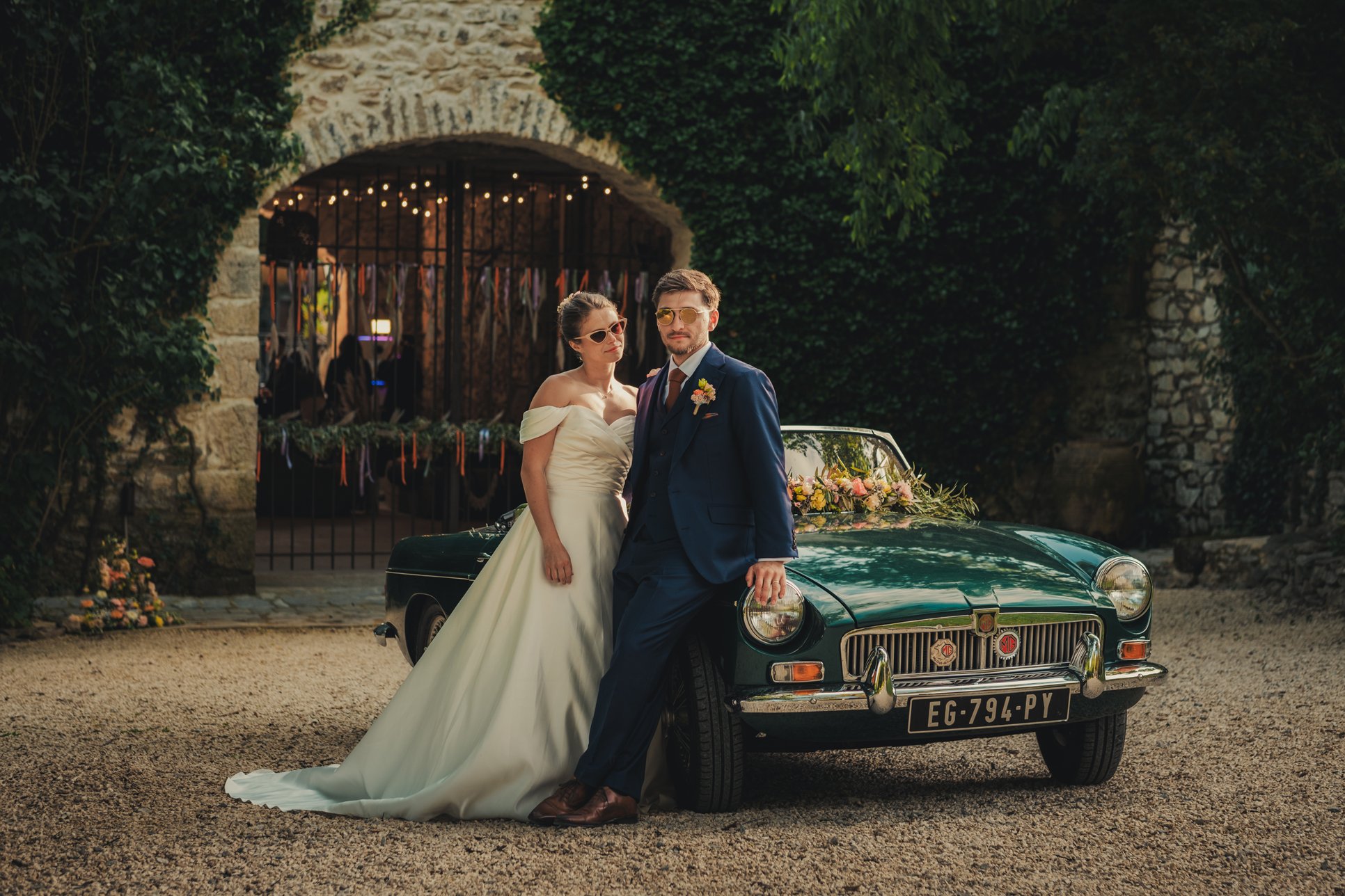 Couple de mariés posant avec une voiture décapotable vintage au Domaine des Rives en Provence