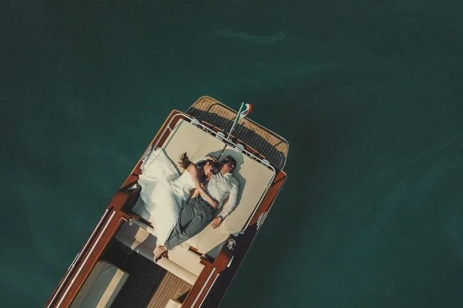 Spring in Lake Como 🪻
Snow still clinging to the peaks.
Bright blue sky, mountains putting on a full show.

A classic wooden boat slicing through the water.
Sun high, everything glowing.

Two people who crossed continents for this and made it count.