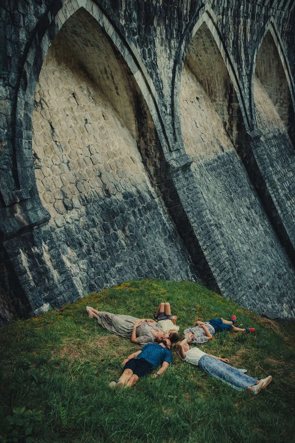 Famille allongée dans l’herbe riant ensemble lors d'une séance photo famille à Roanne