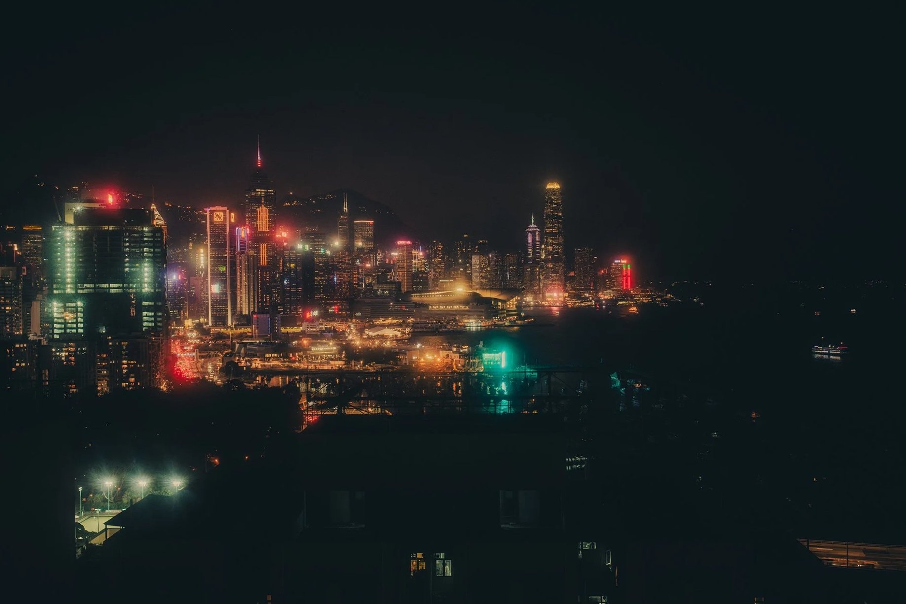 Hong Kong at night time from a rooftop view with neon lights.
