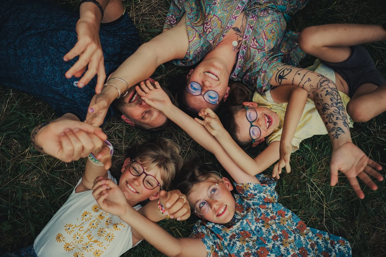 Parents et enfants riant ensemble pendant une séance photo famille naturelle à Roanne