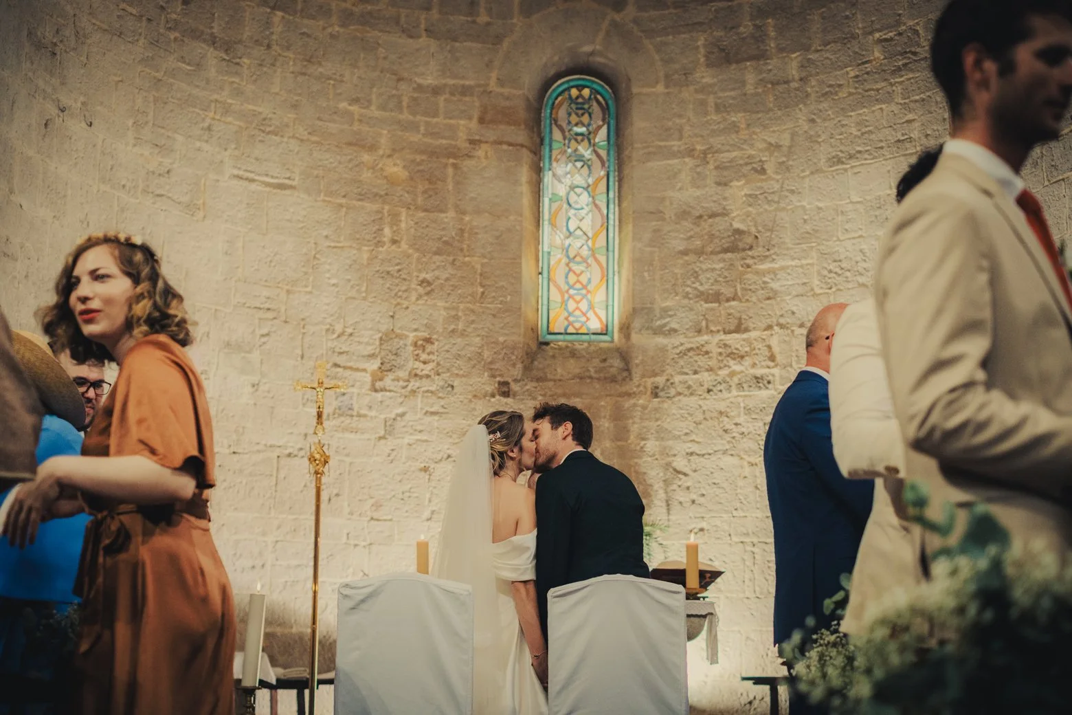 Bride and groom kissing during a wedding ceremony in a small church in Provence France.