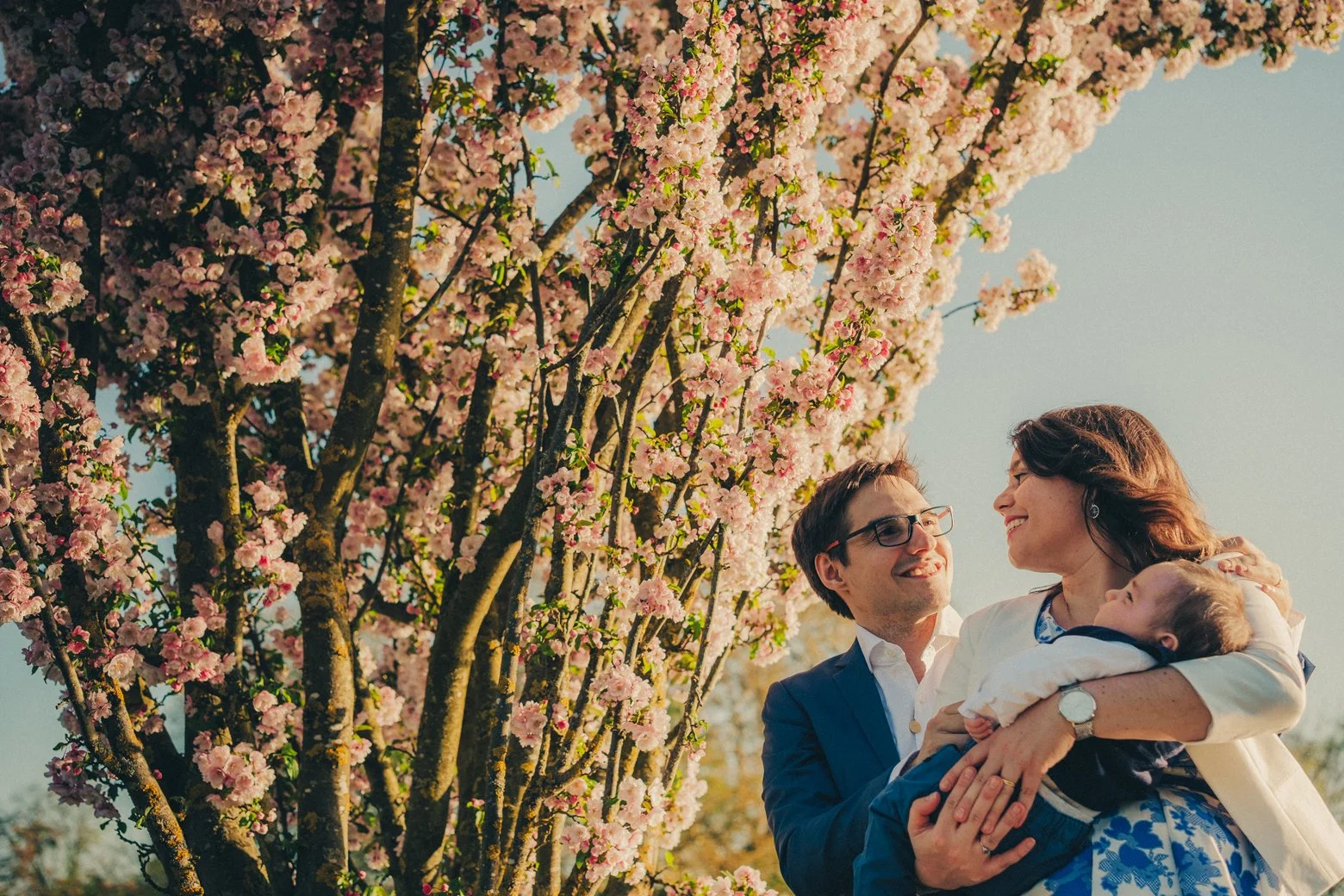 Parents tenant leur nouveau-né près des fleurs en bloom lors d’une séance photo famille à Lyon