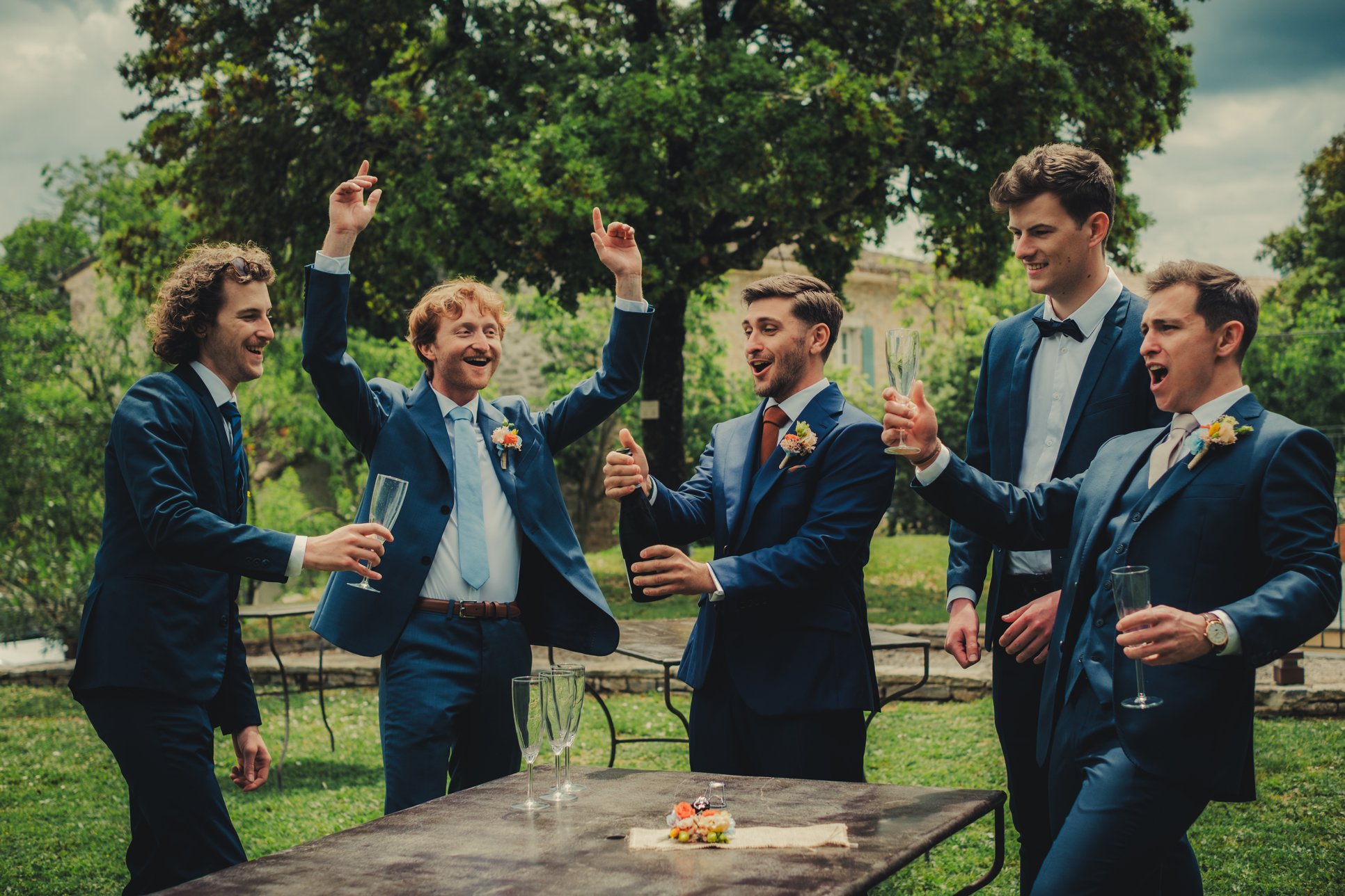 Marié et garçons d’honneur ouvrant une bouteille de champagne pendant les préparatifs