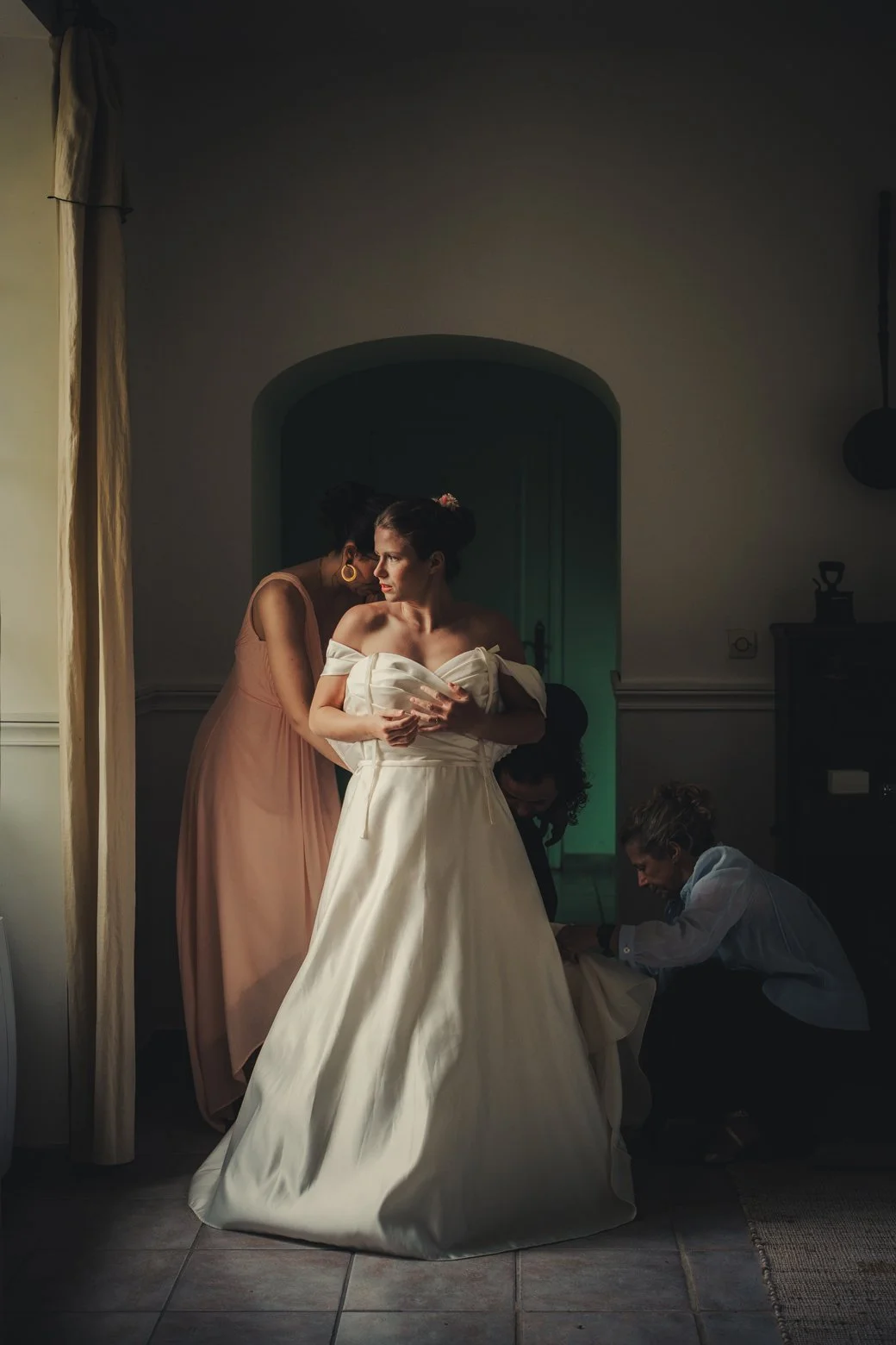 Mariée aidée par sa famille et ses amies pour enfiler sa robe au Domaine des Rives