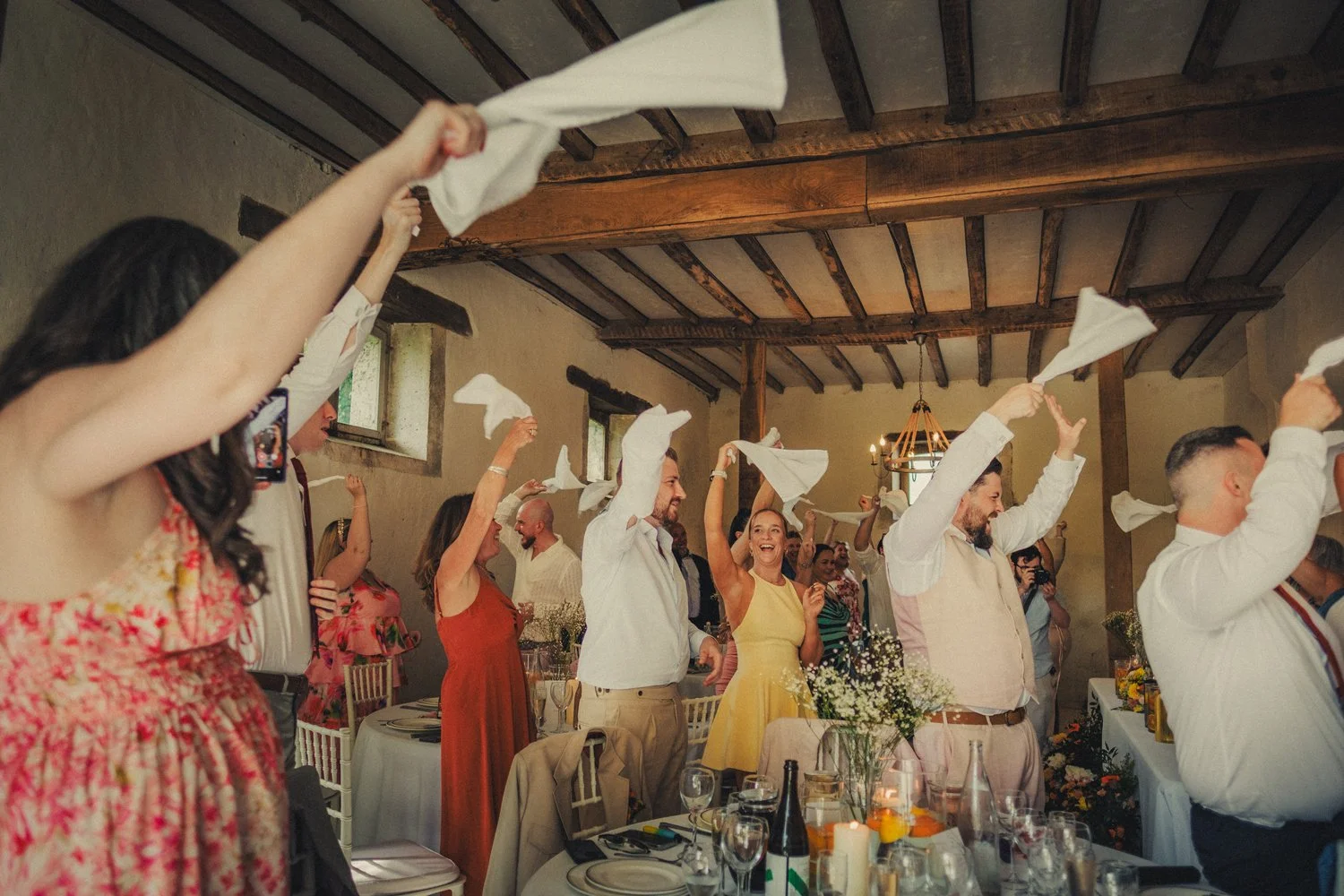 Guests cheering and waving napkins during wedding dinner