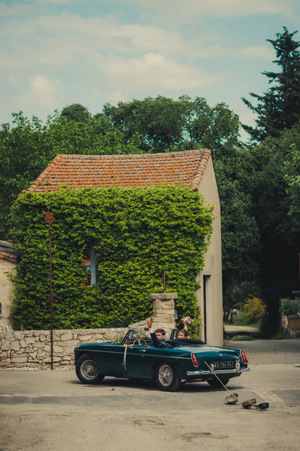 Mariés quittant l’église en voiture vintage sous les applaudissements